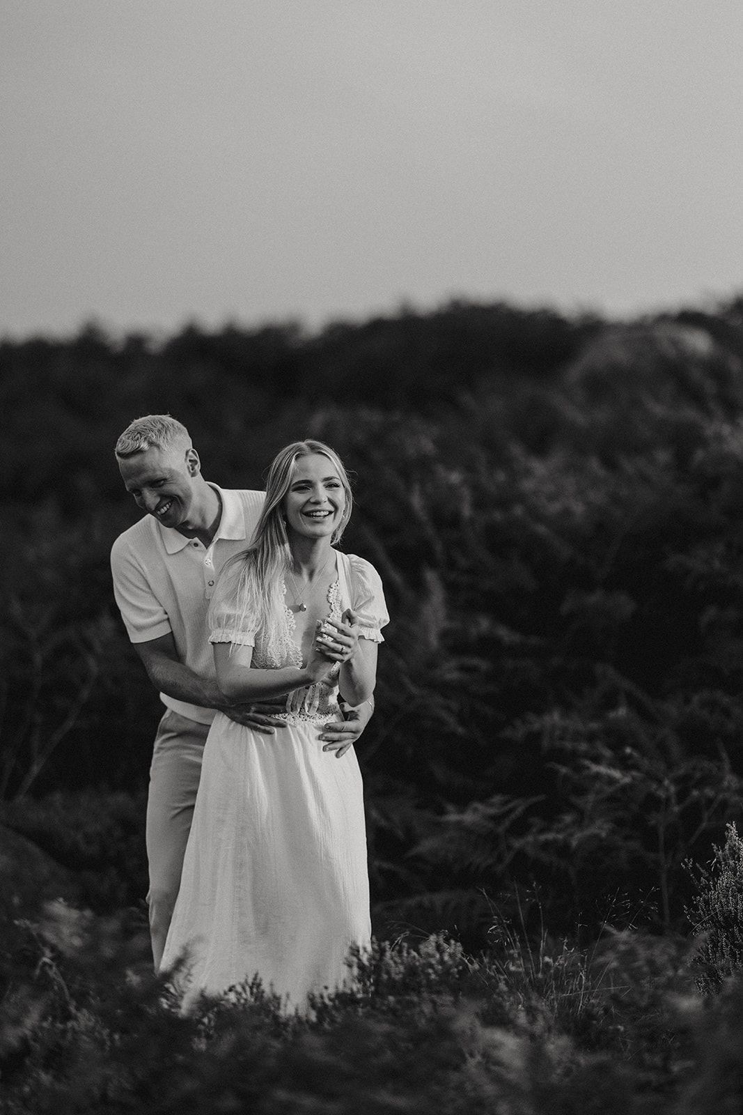 Black and white outdoor portrait of a couple embracing in a natural setting with trees in the background. Taken by Lincolnshire photograpers