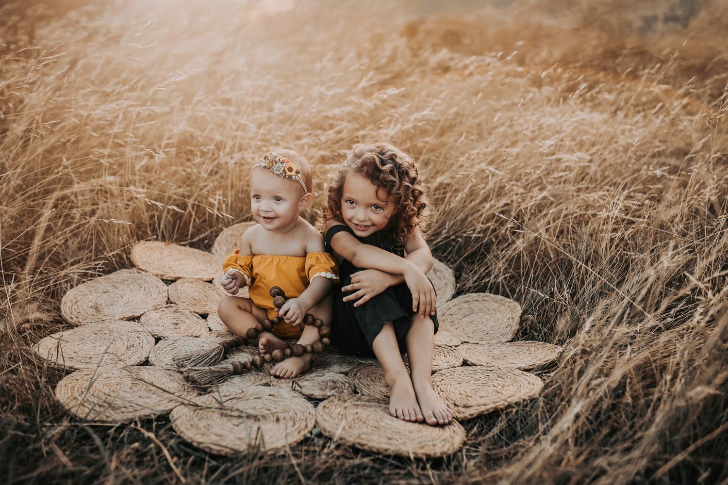 two little sisters snuggling in a field of golden grass