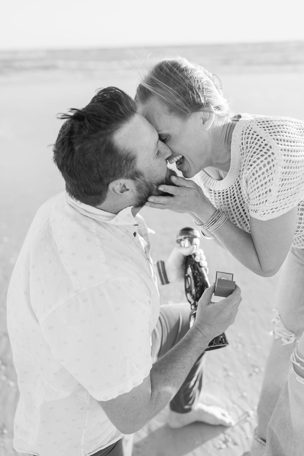 A candid moment of a couple after saying yes on the beach