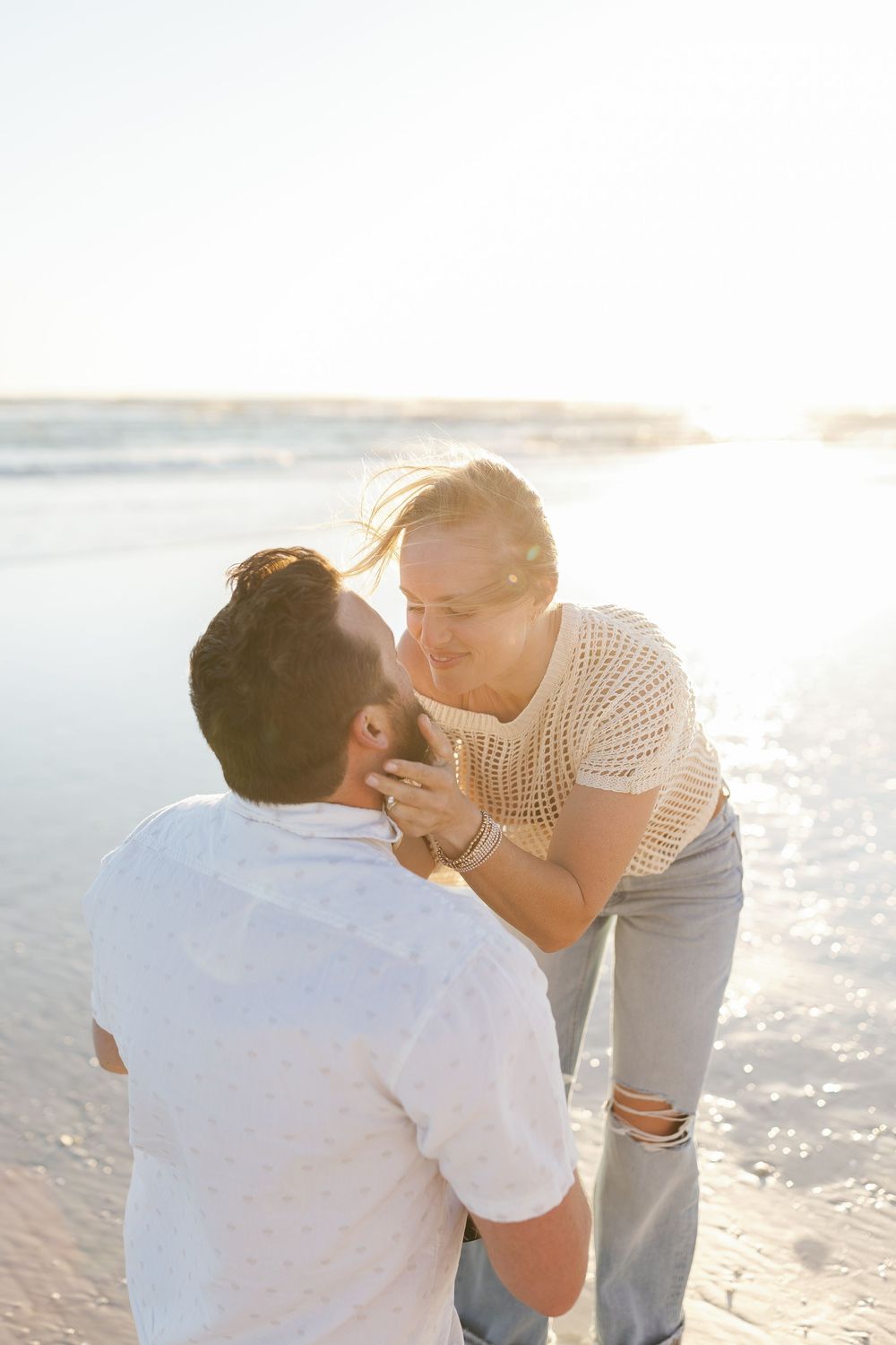Couple sharing a kiss on Siesta Key beach during golden hour after a proposal