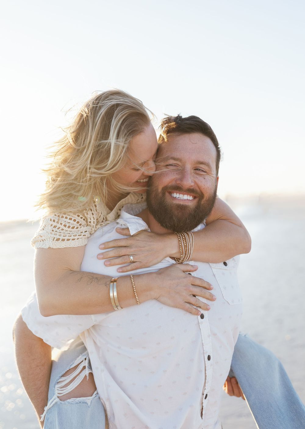 Woman laughing on his back during playful piggyback ride by the water