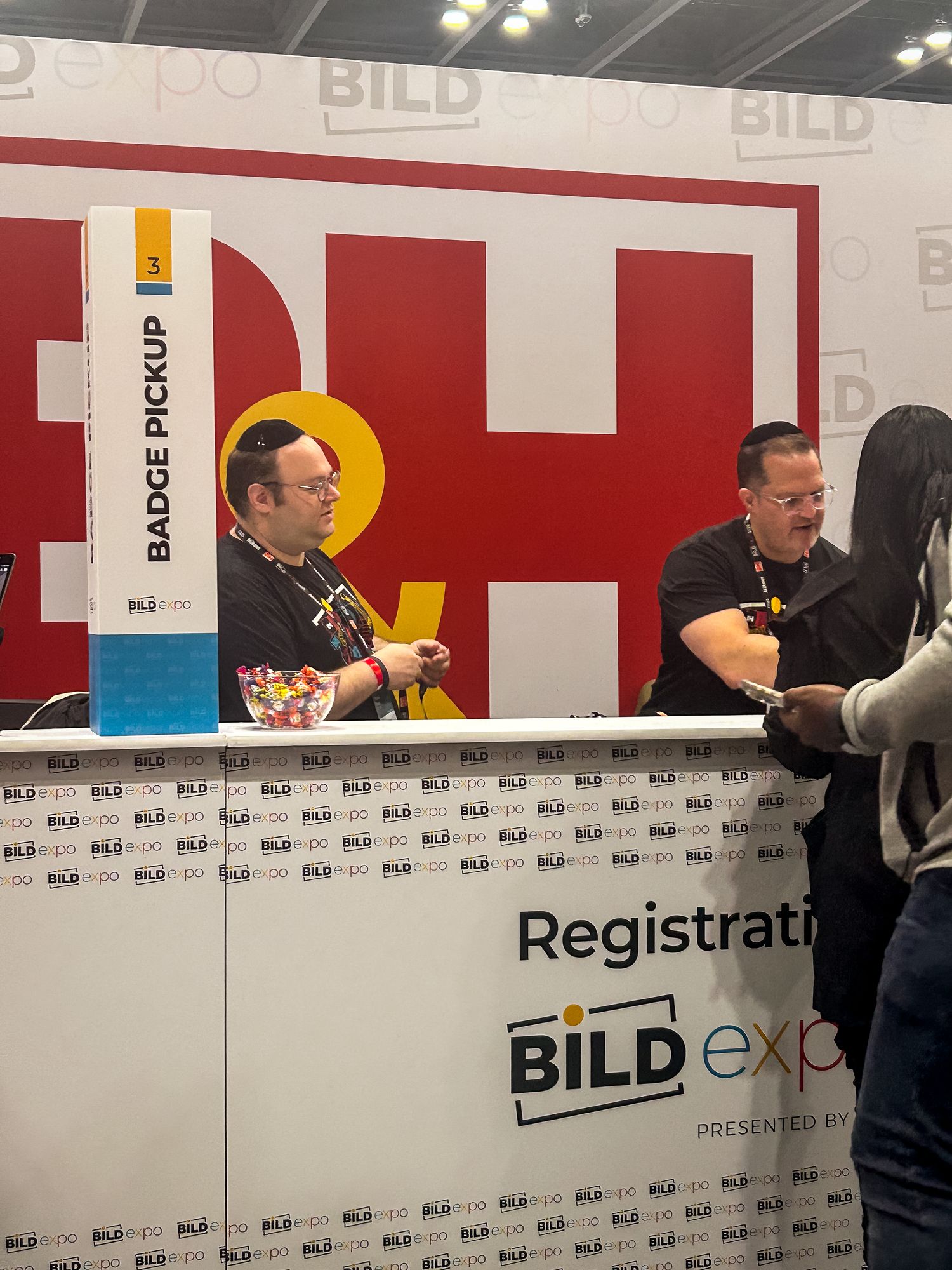 Conference registration desk with branded backdrop and staff members helping attendees at a BILD event.