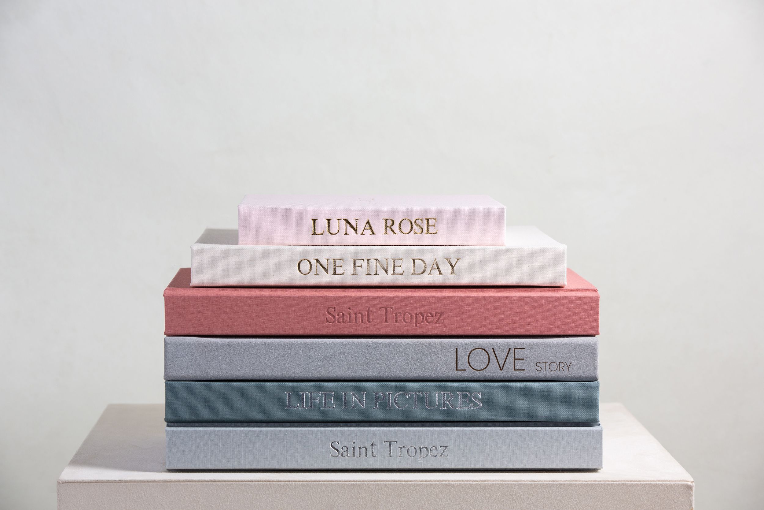 Stack of elegant pastel-colored books arranged horizontally against a white background.