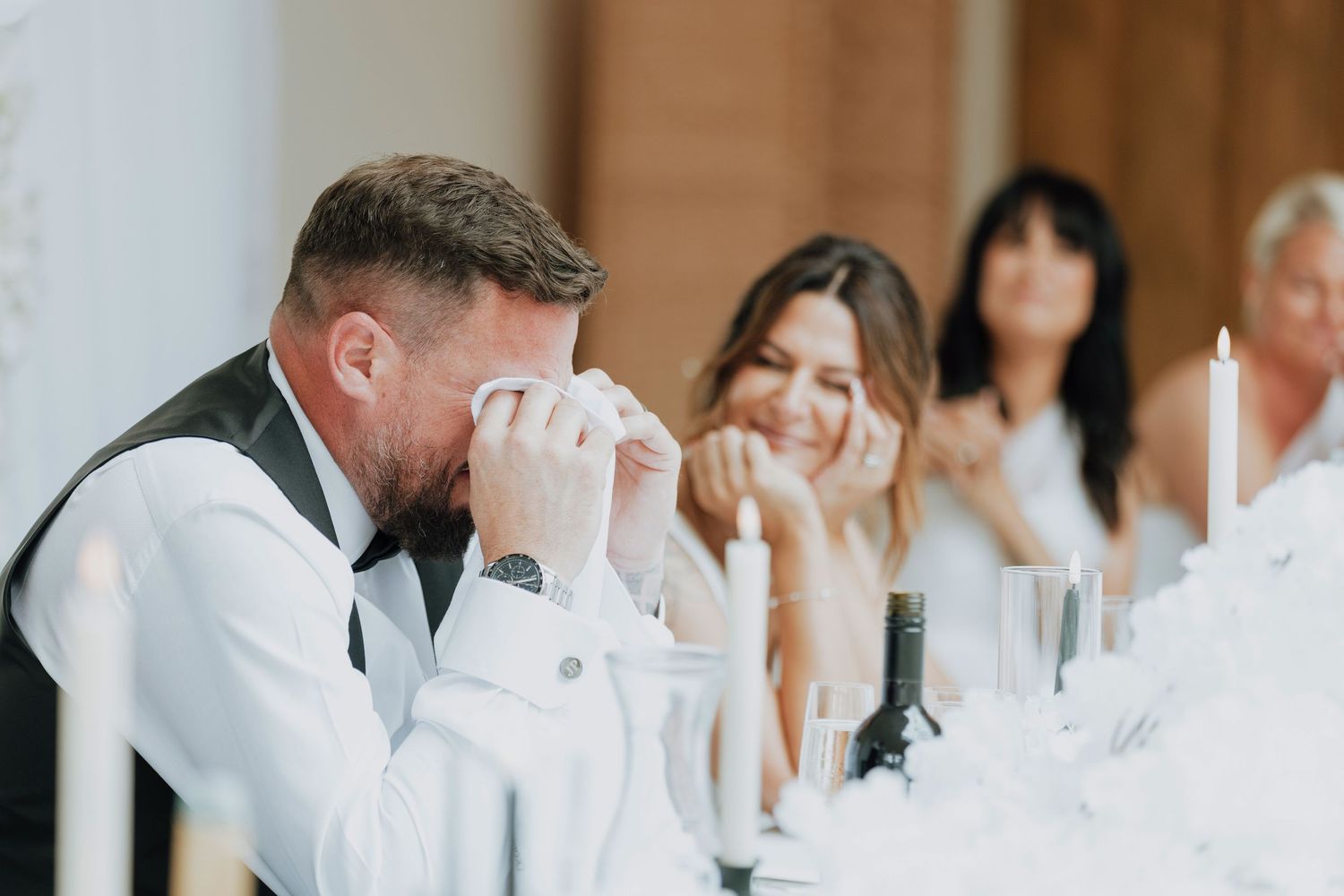 A row of seated dinner guests in white attire attending a formal event at a banquet table.