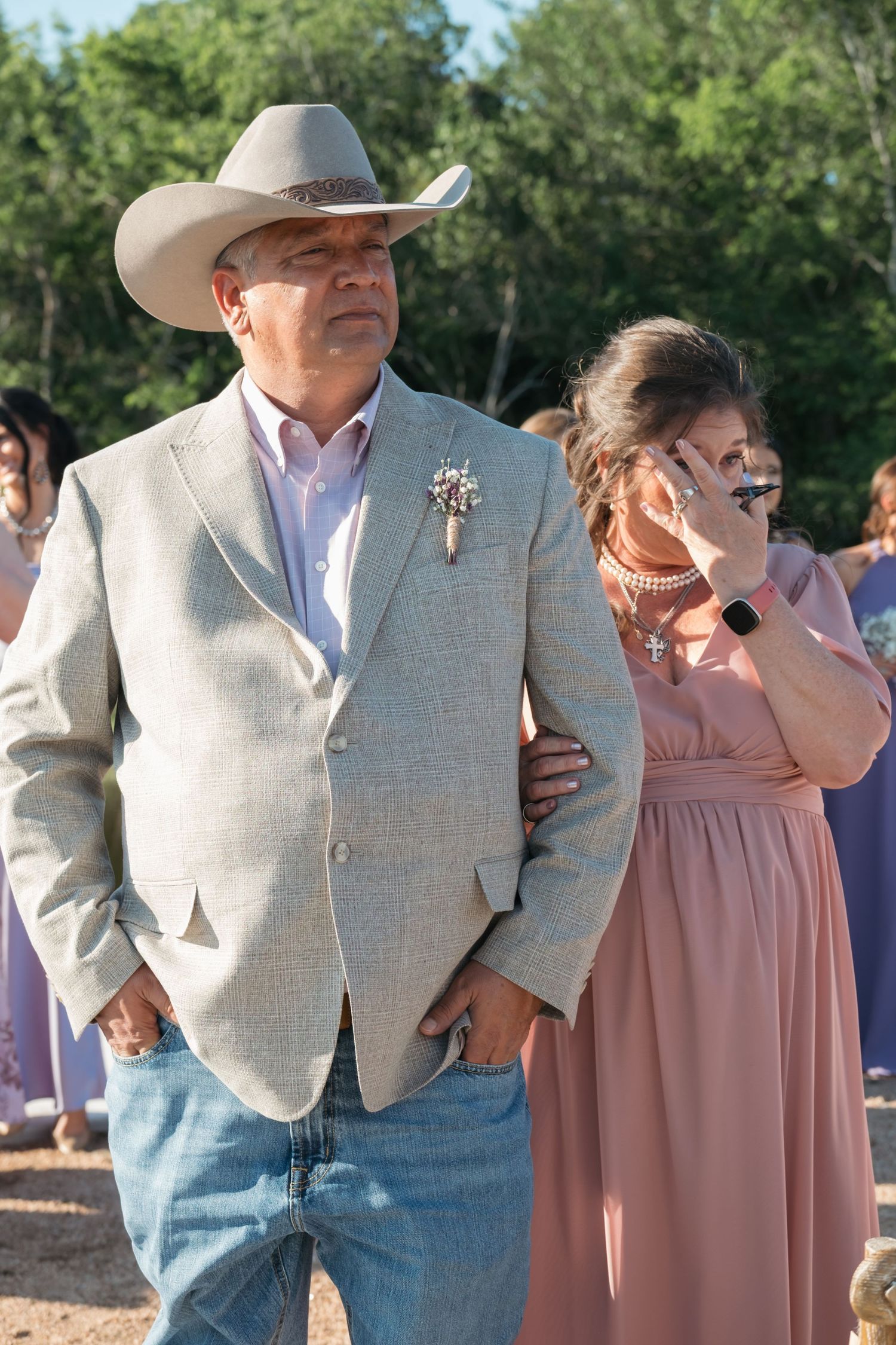 Dancing couple in western attire with man wearing cowboy hat and light blazer moves across outdoor dance floor.