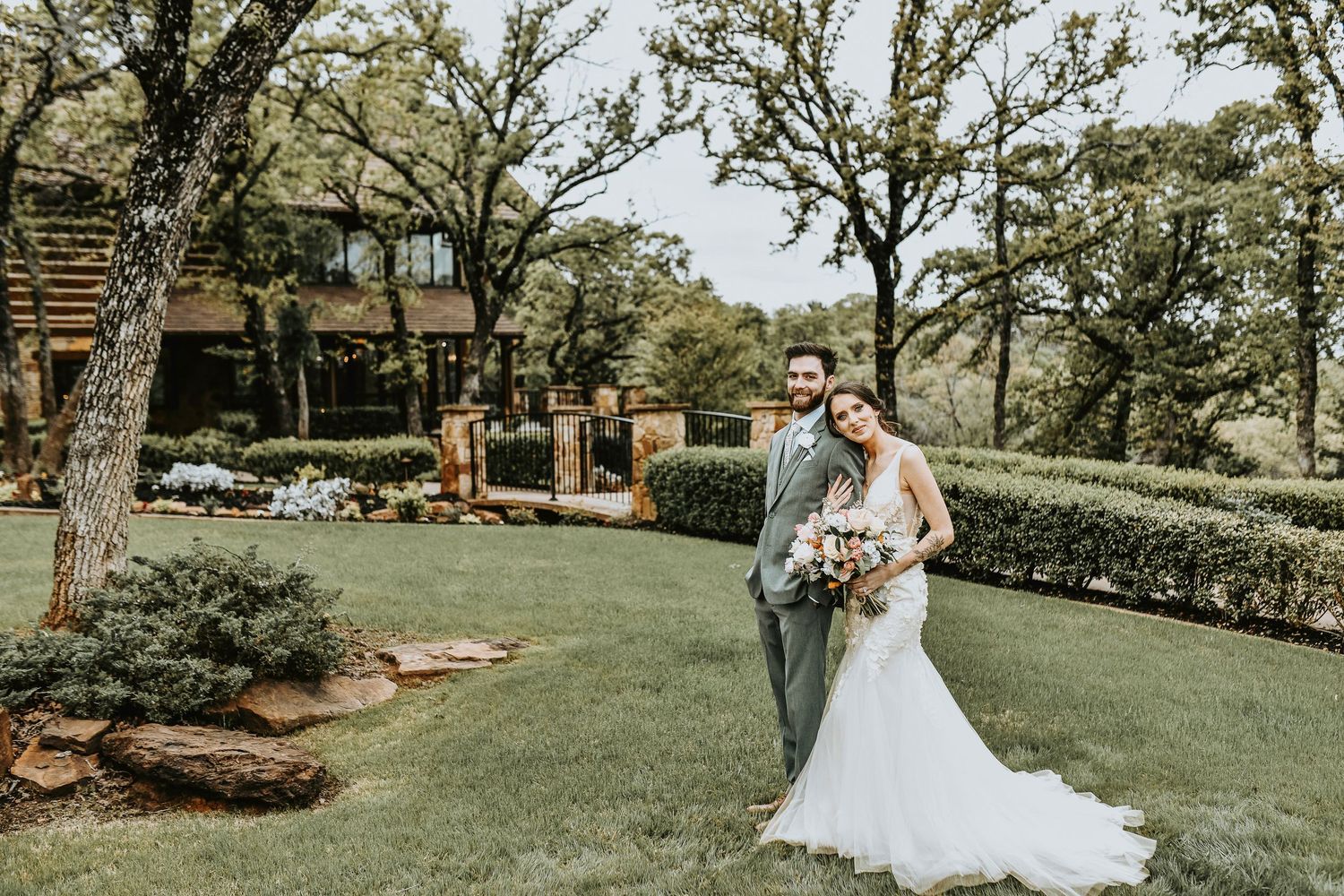 Romantic portrait of bride and groom during golden hour, with spring blooms and lush greenery in the background at The Lodge