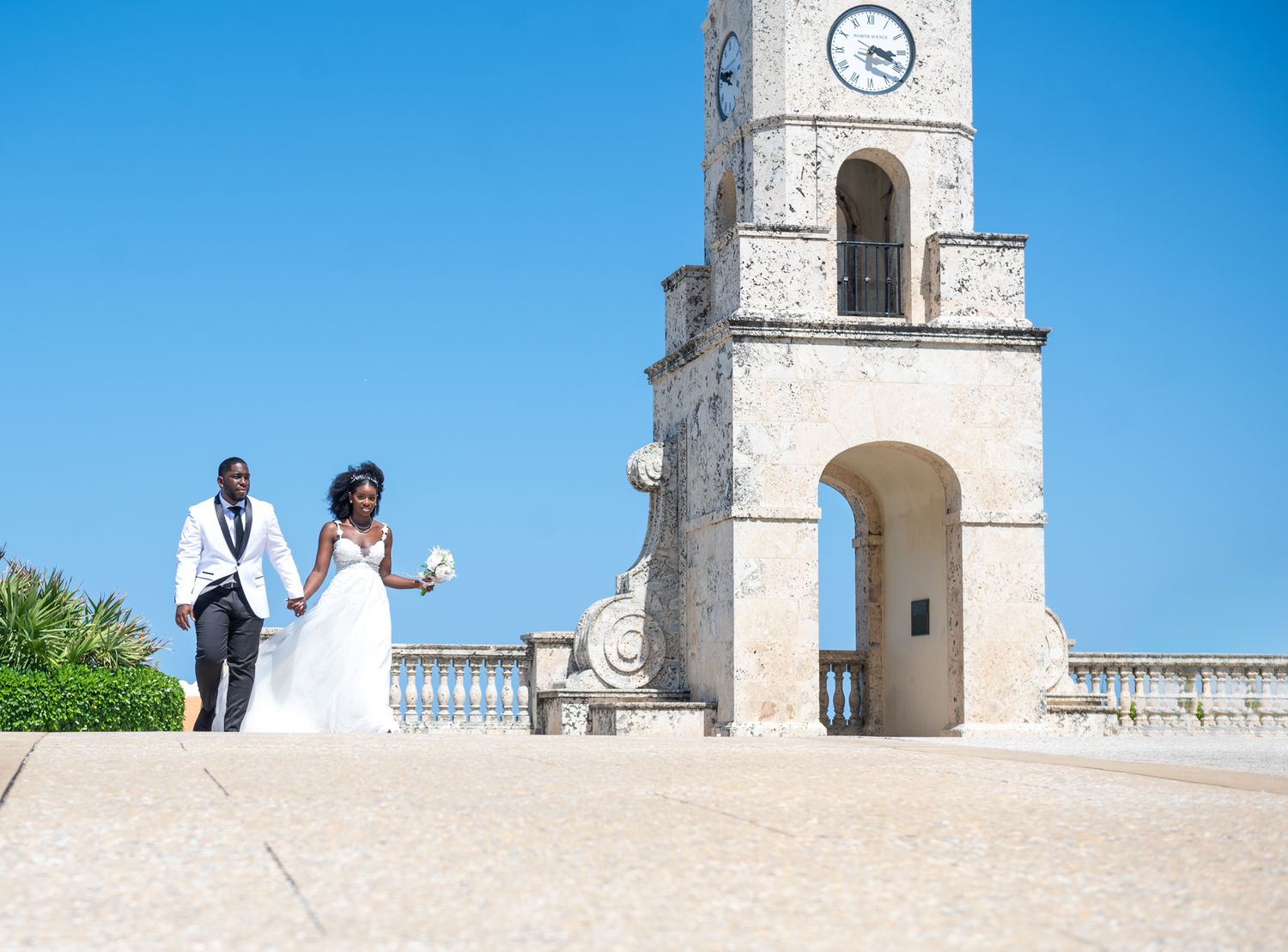 Palm Beach wedding photographers capture the bride and groom crossing the street at the Worth Avenue Clock tower in Palm Beach, Florida.