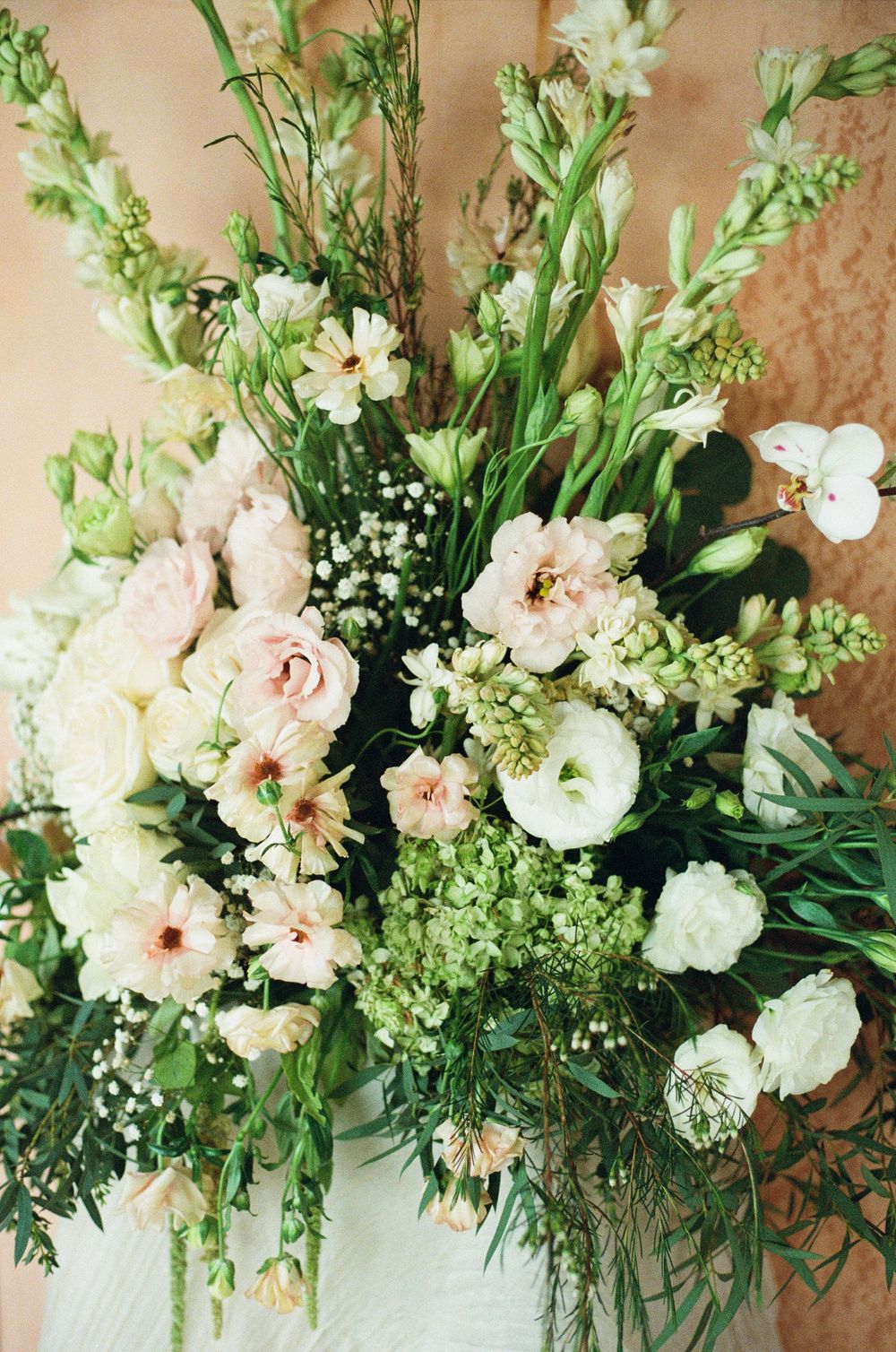 Lush garden-style floral arrangement with white and blush blooms mixed with delicate greenery.