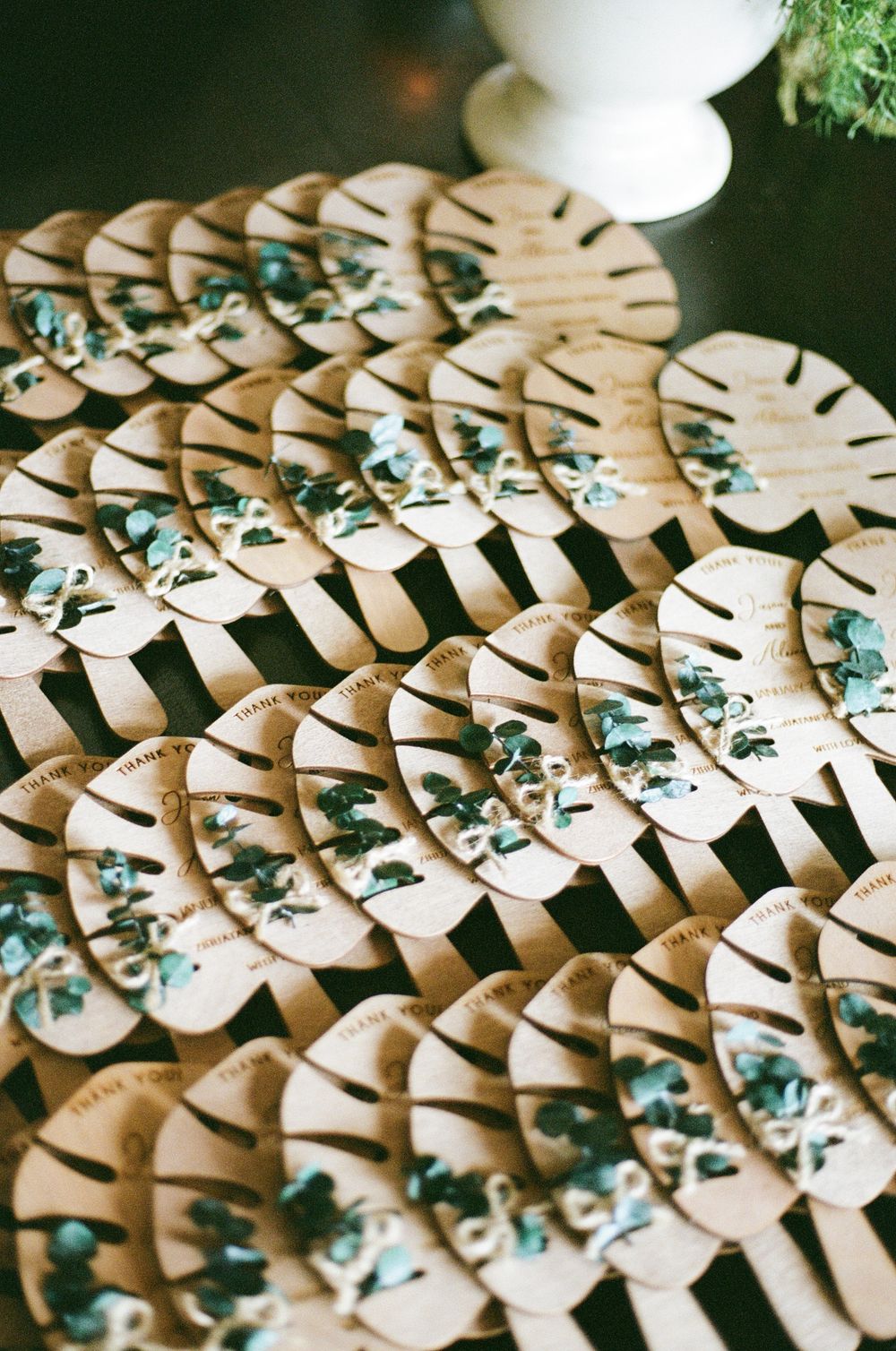 Decorative paper palm leaf place cards arranged in rows with delicate floral details.