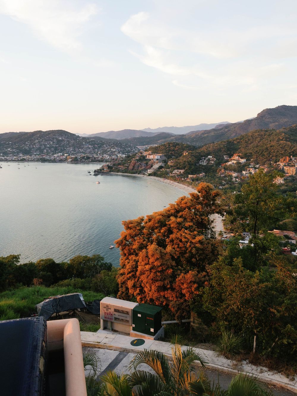 Scenic coastal view of a bay surrounded by mountains and orange-colored trees.