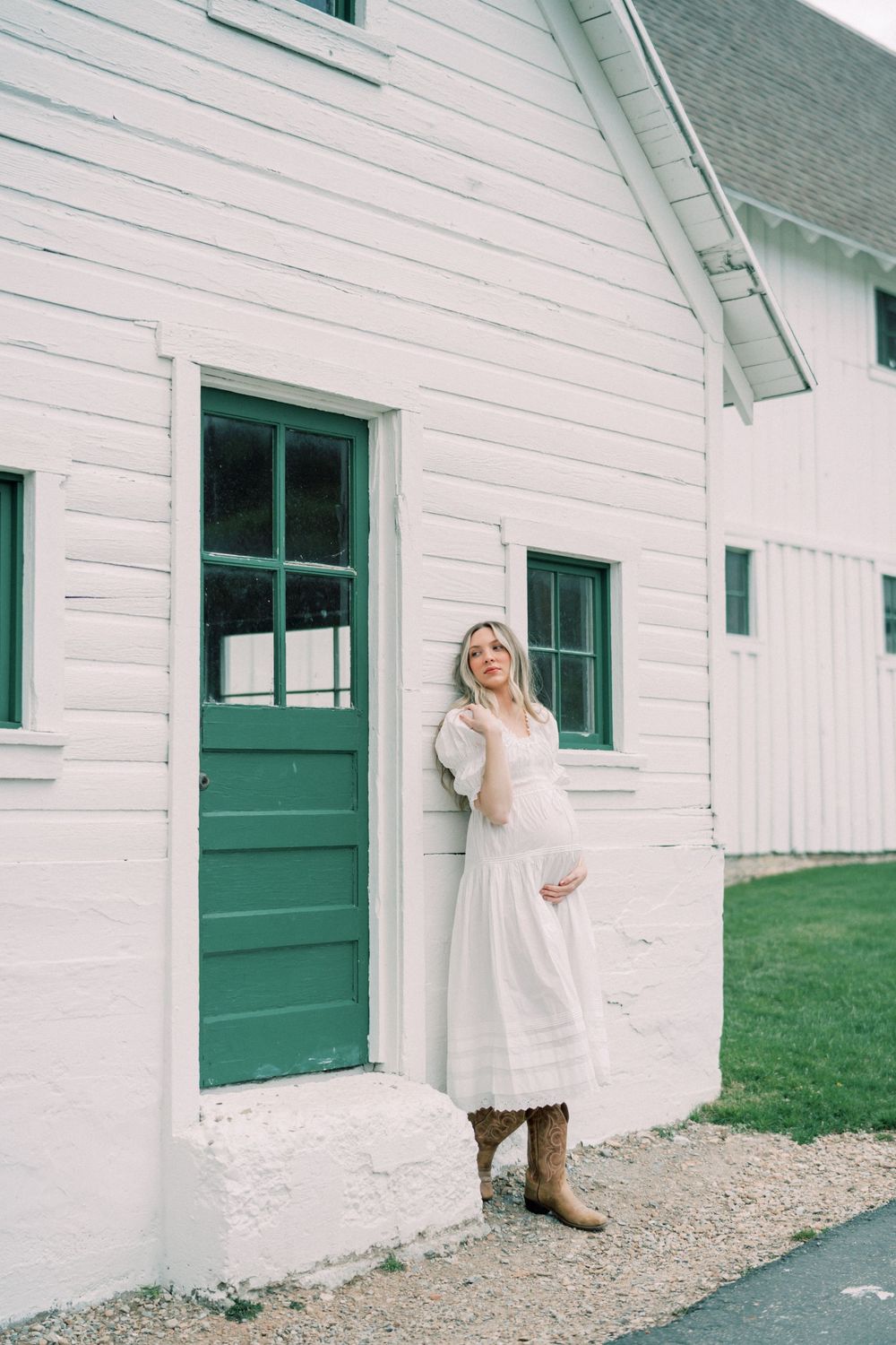 White farmhouse exterior with green door and window trim featuring a rustic countryside aesthetic.
