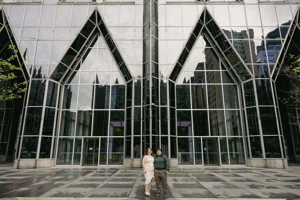 Modern glass building facade with triangular peaks and reflective windows creates dramatic architectural entrance.