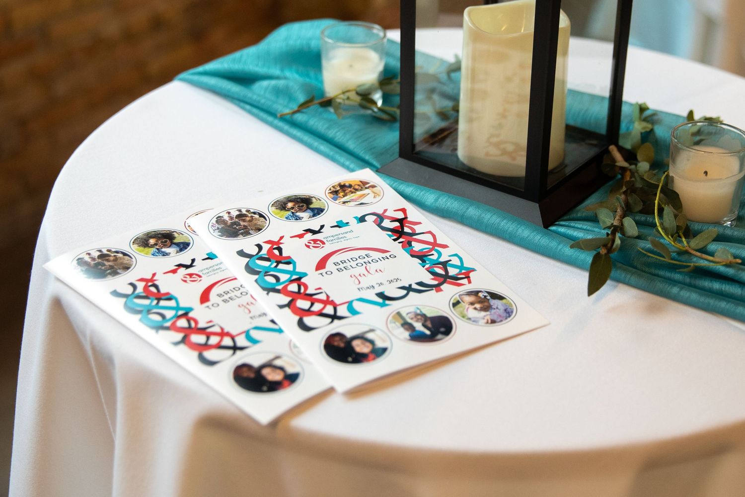 Wedding tic-tac-toe game setup on white tablecloth with teal decor and lantern centerpiece.