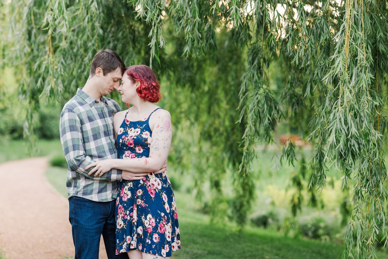 A romantic couple embracing beneath a weeping willow tree in a garden setting at Cantigny Park