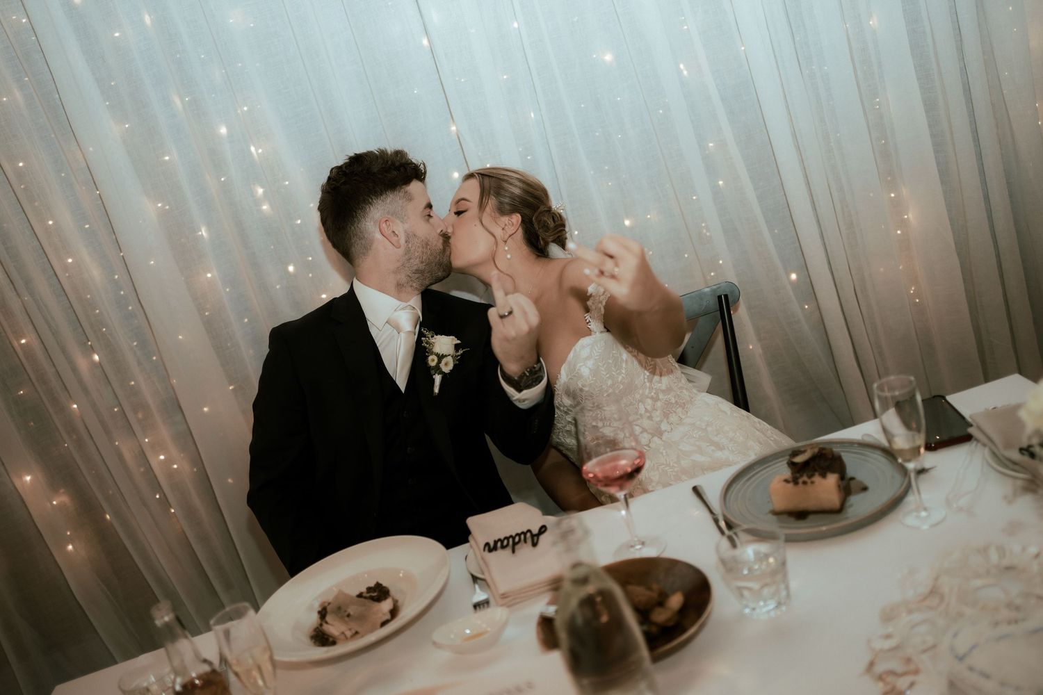 Newlyweds sharing an intimate moment at their reception dinner table.