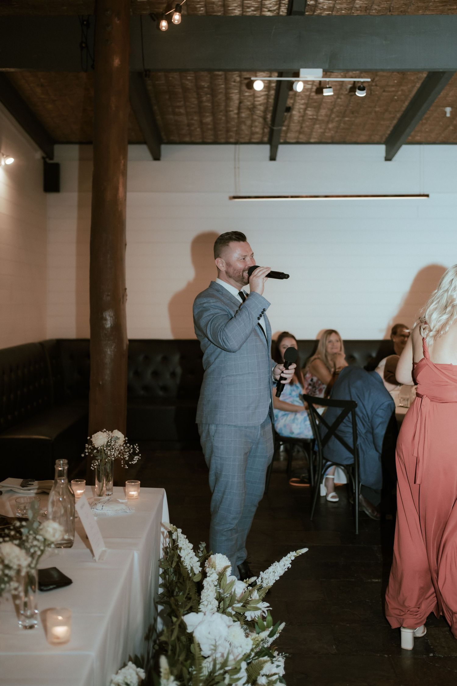 Guest giving a speech at wedding reception in modern industrial venue.