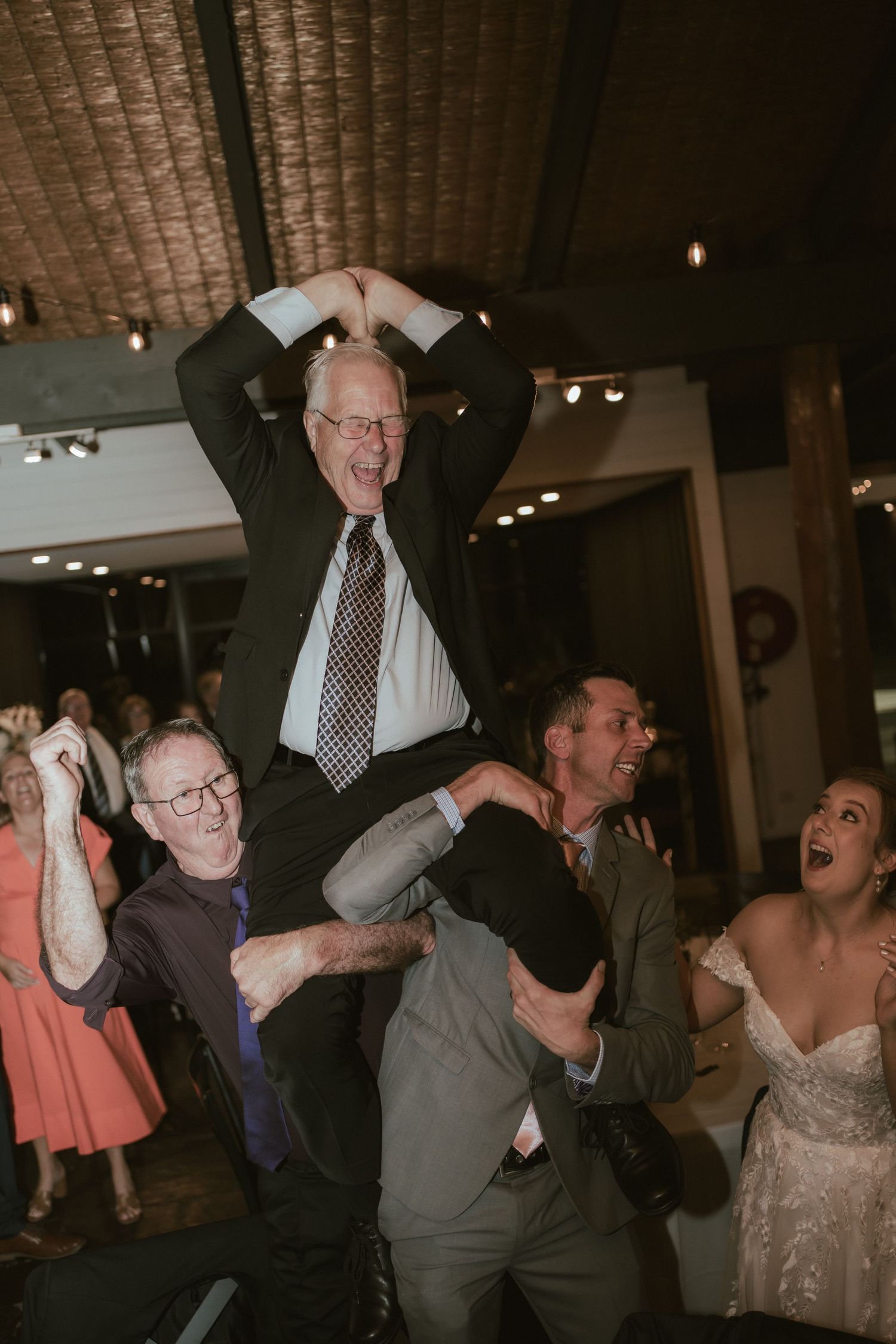 Wedding guests lift and celebrate during reception party.