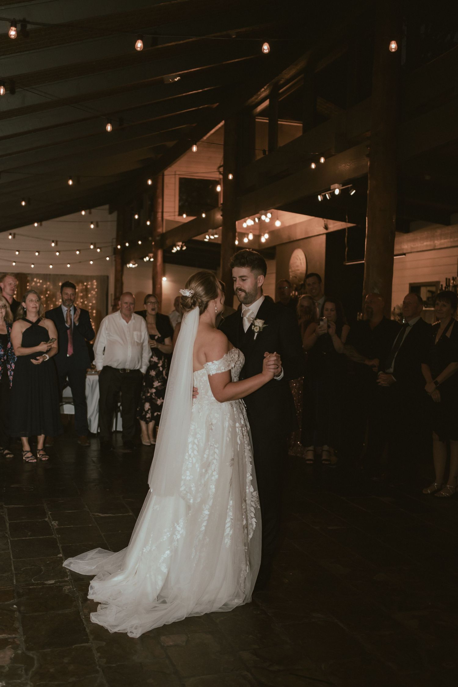 First dance at wedding reception with string lights and elegant decor.