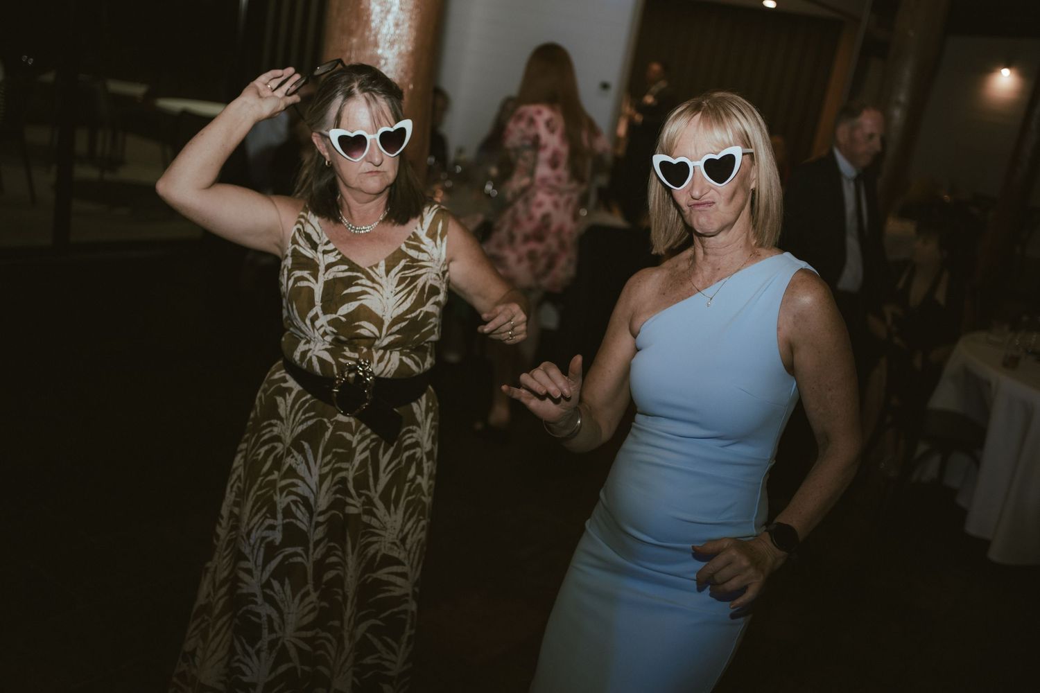 Party guests wearing sunglasses and dancing at a wedding reception.