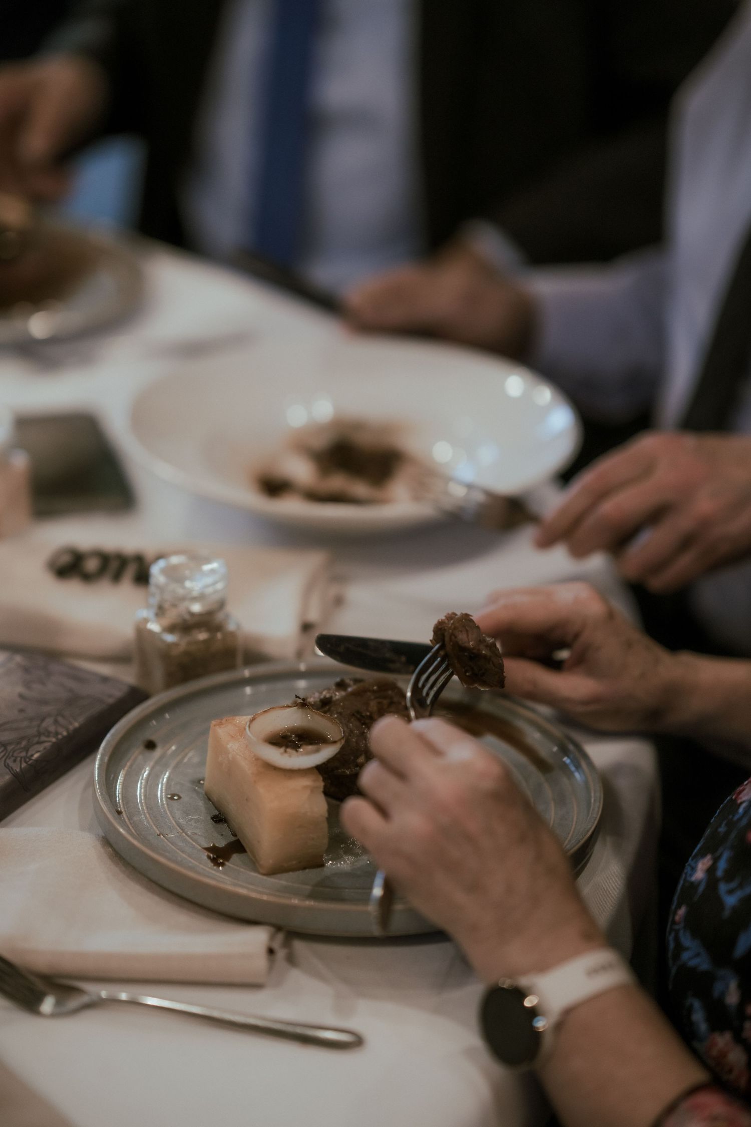 Close up of hands cutting and eating wedding cake at reception dinner.
