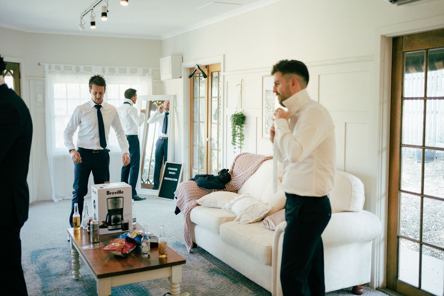 Wedding preparation scene in bright room with white couch.