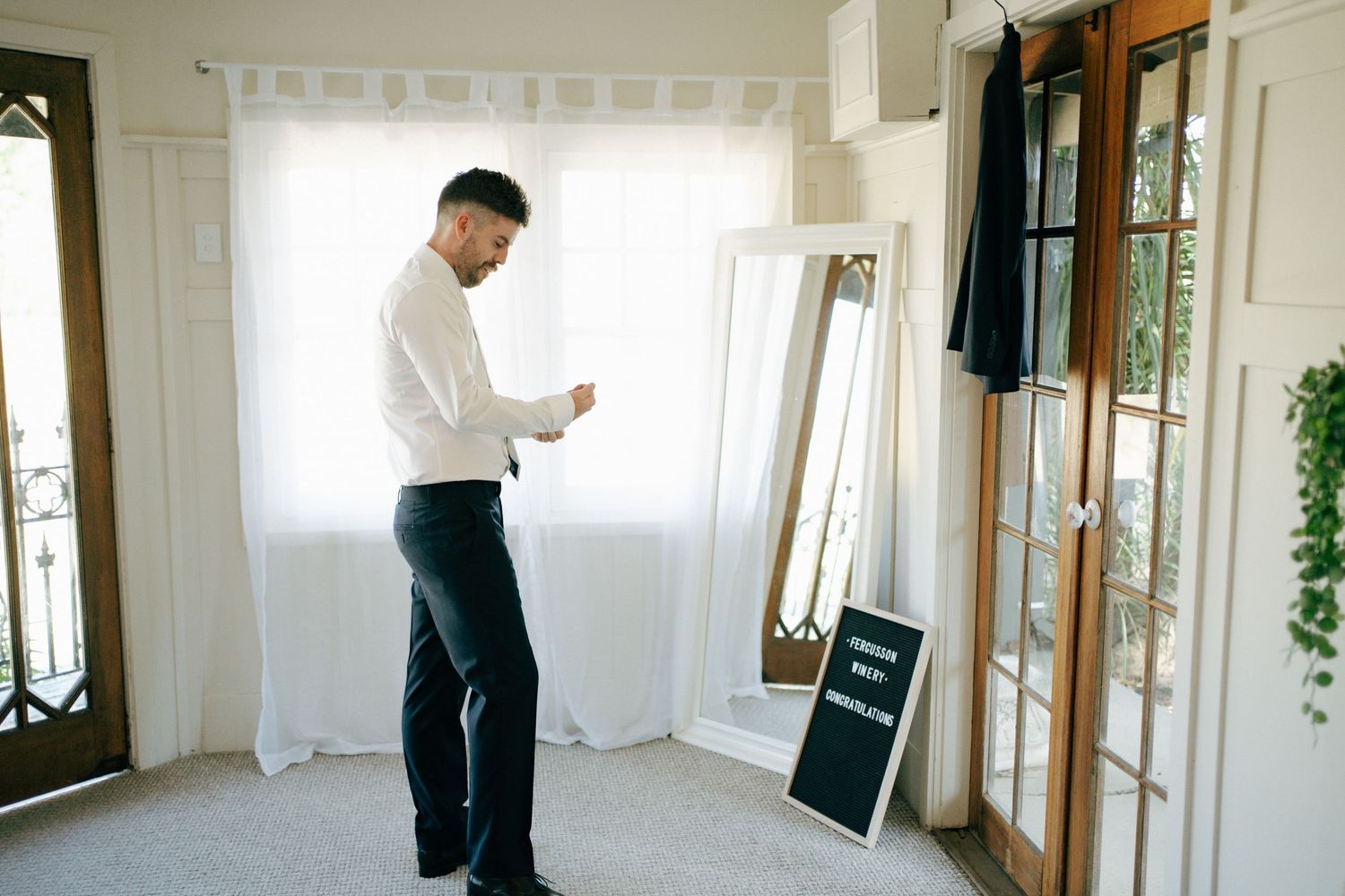 Person in white shirt getting ready in room with mirrors and chalkboard sign.
