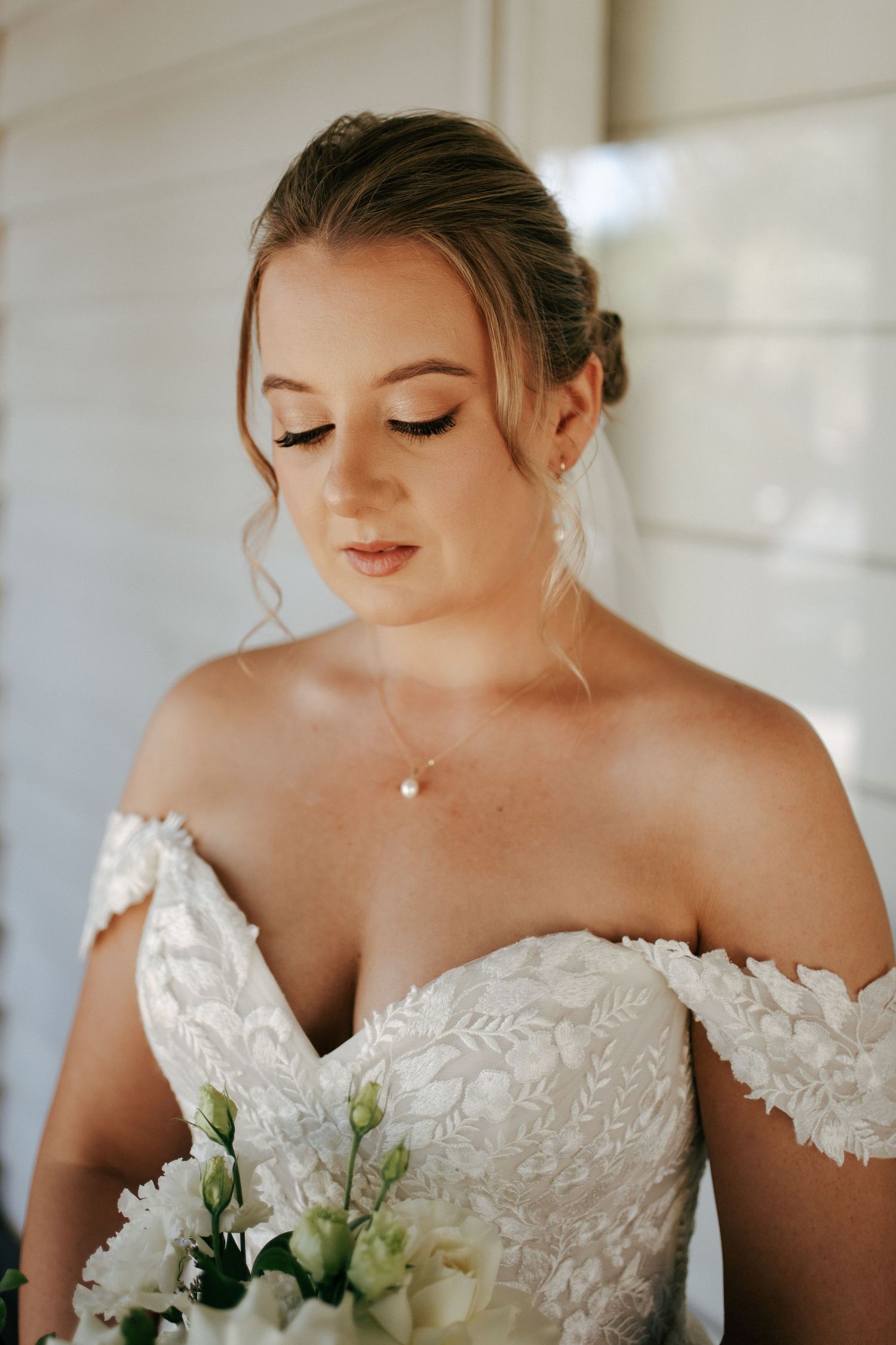 Close up bridal portrait showcasing lace bodice detail, delicate necklace and soft makeup.