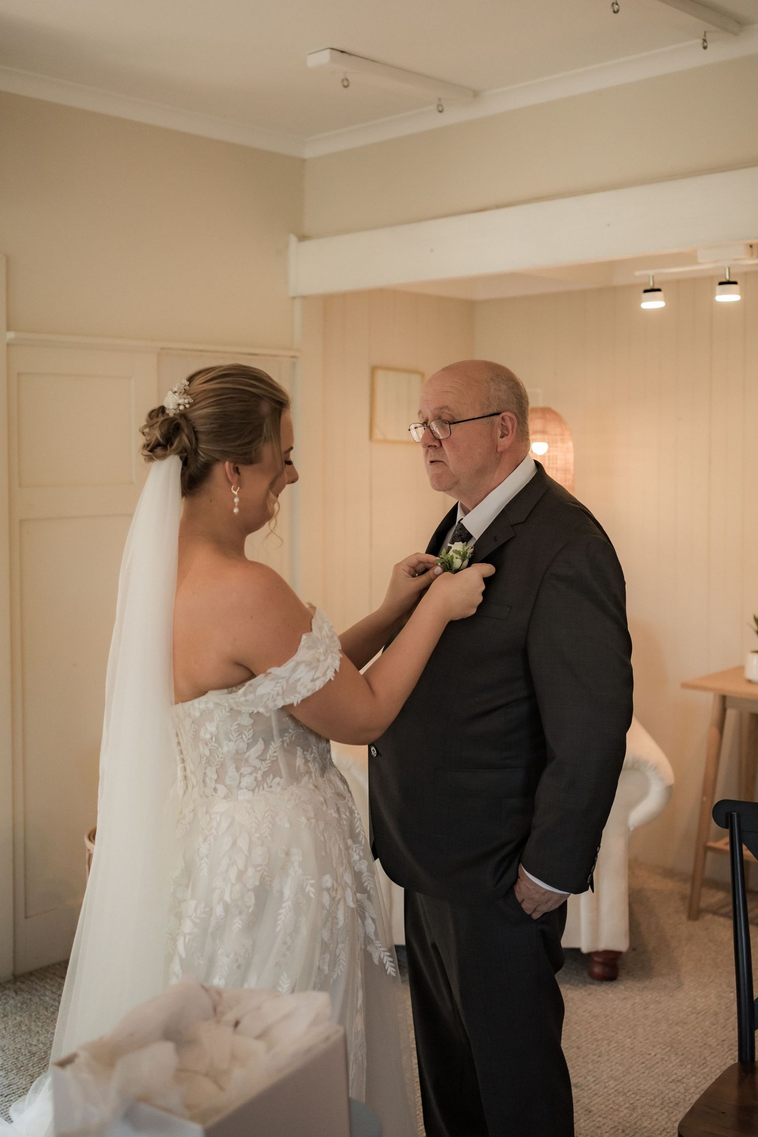 A tender moment between formal-dressed wedding couple during preparation.