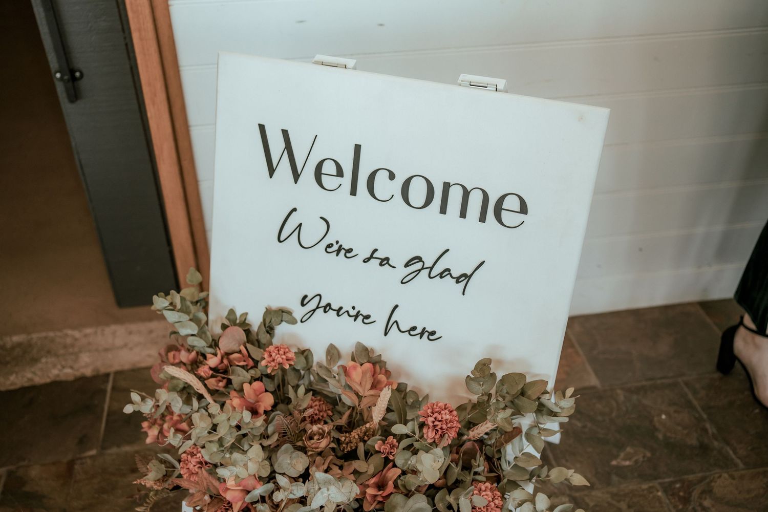 Welcome sign with floral decorations at a winery wedding.