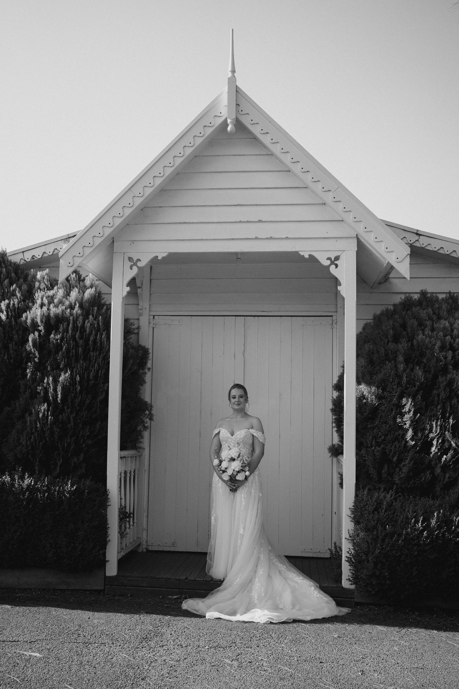 An elegant wedding dress photographed under a charming white chapel entrance portico.