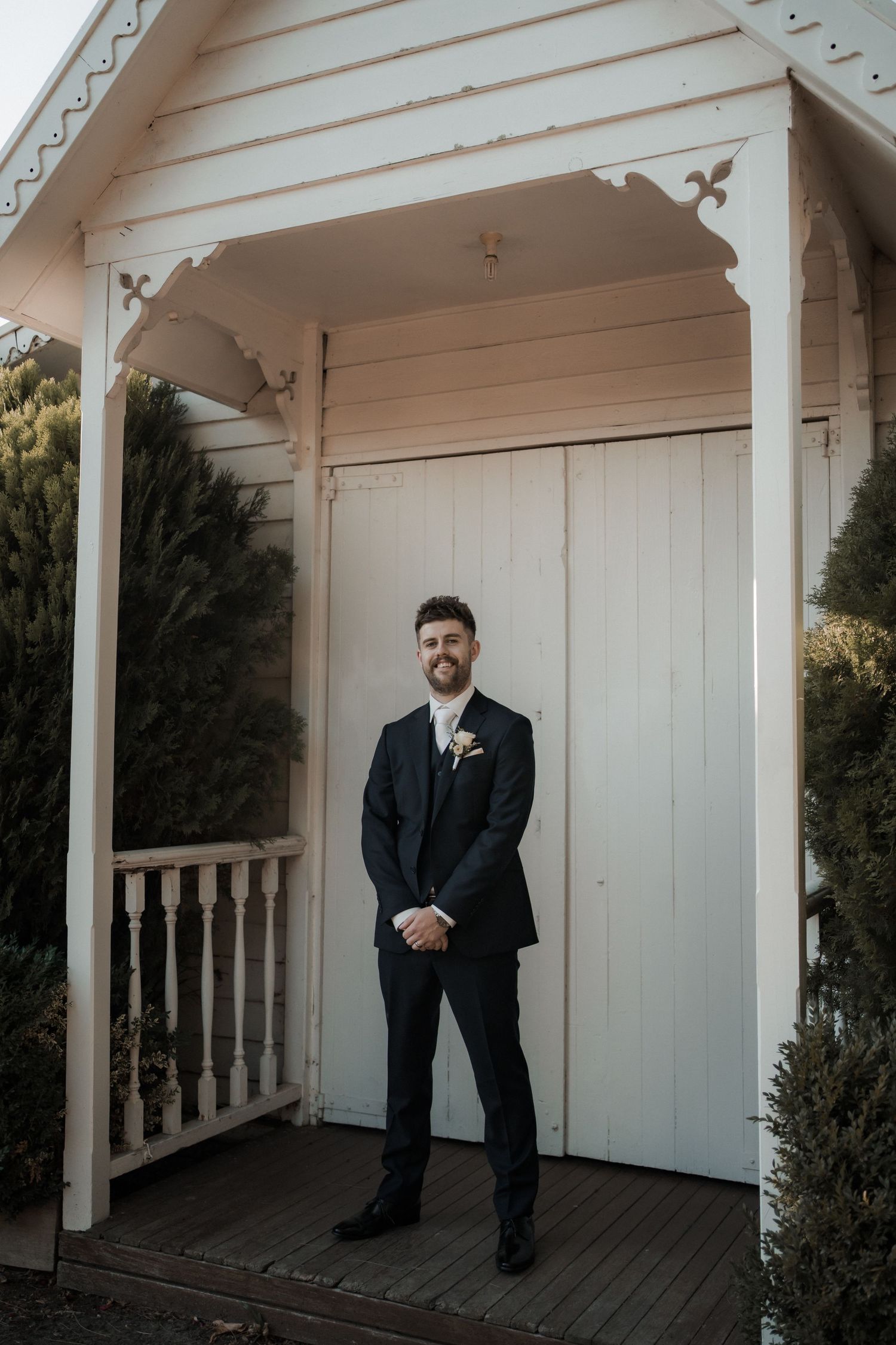A formal portrait in front of a white chapel entrance with decorative trim details.