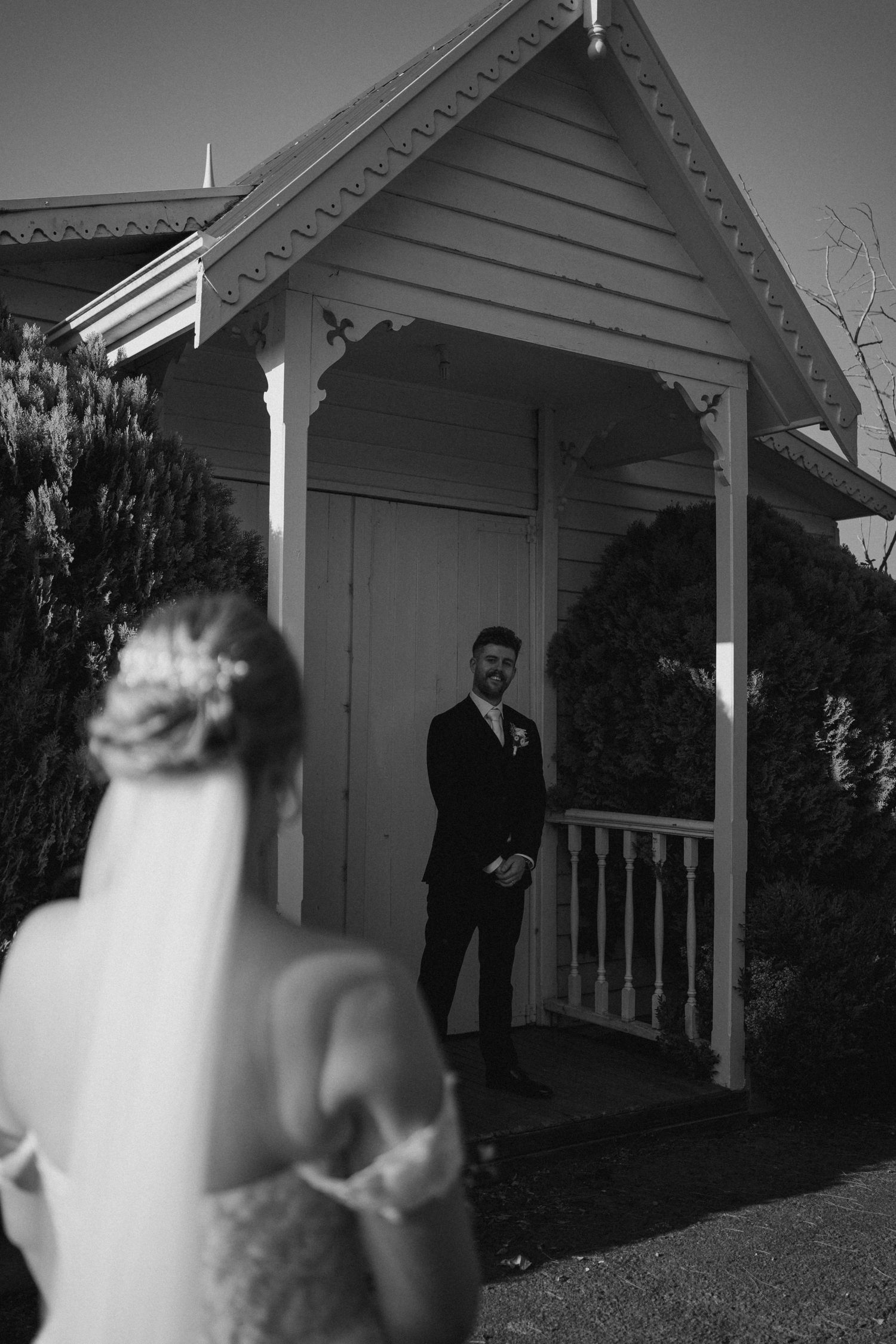 Black and white wedding photo capturing a romantic first look moment at a chapel entrance.
