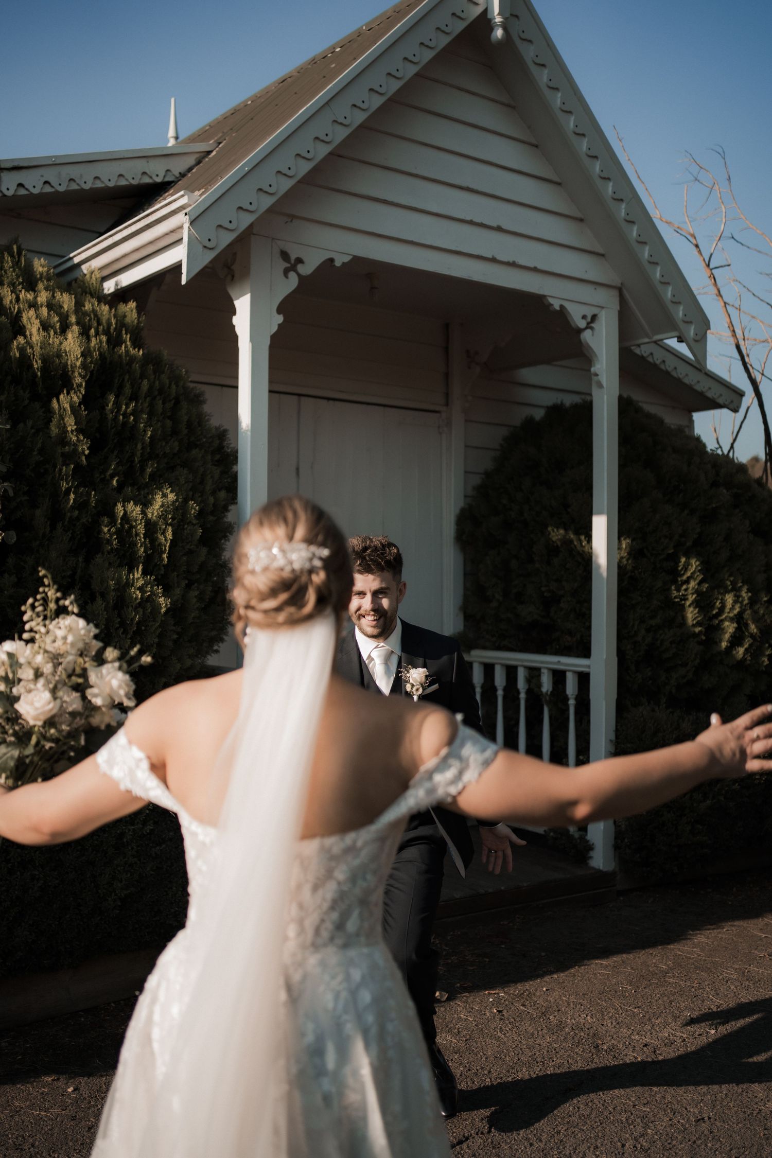 Joyful first look moment between newlyweds at a white chapel entrance.