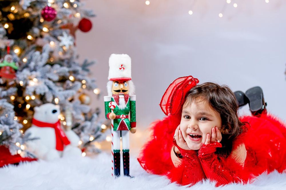 Holiday portrait with nutcracker decoration and Christmas tree in background.