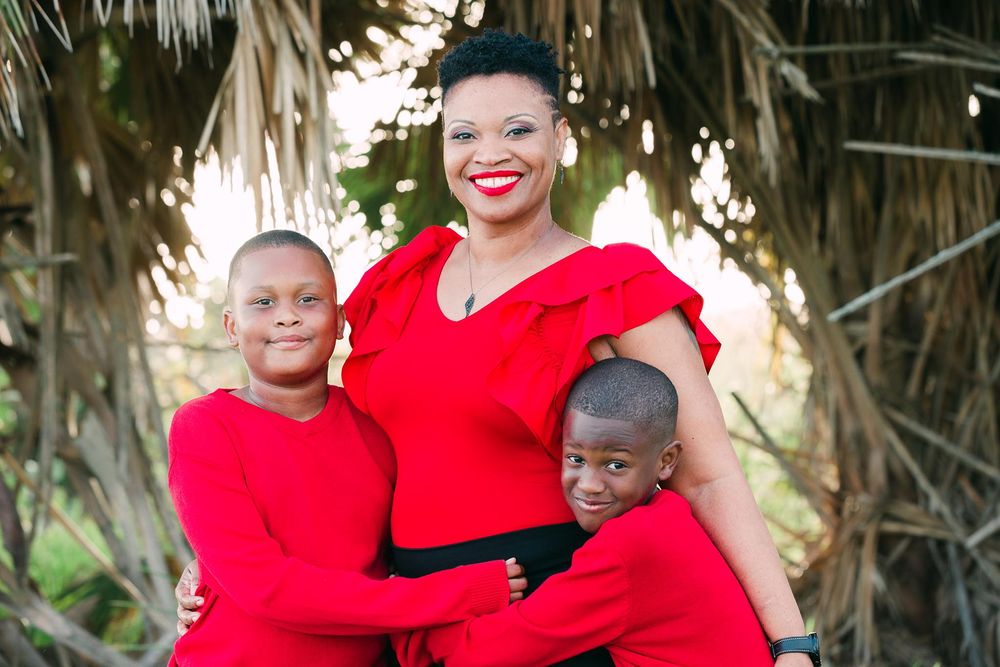 Family portrait of three people wearing matching red outfits outdoors.