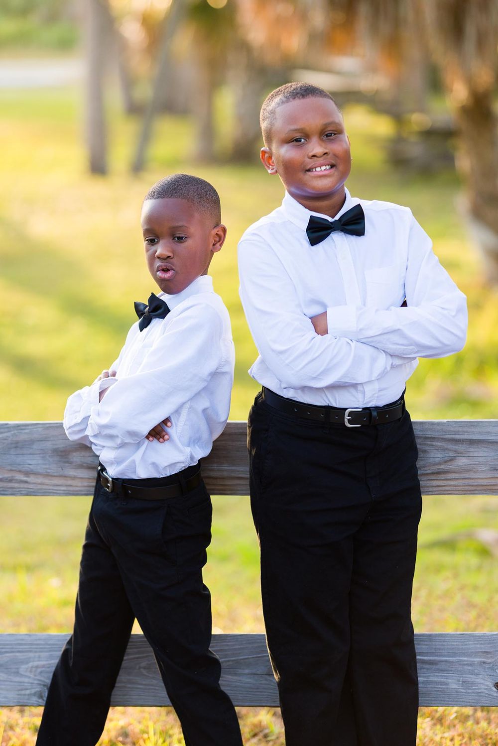 Two young boys in formal black and white attire playfully pose together outdoors in a series of candid photos.