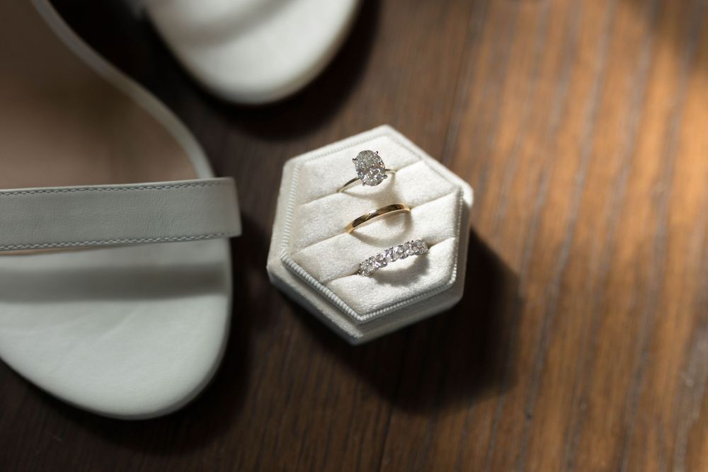 Wedding rings displayed in a white hexagonal ring box on wooden surface.