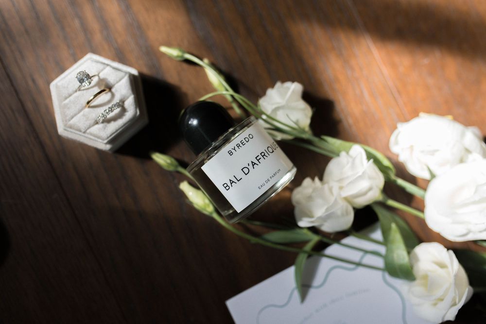 White roses and a perfume bottle arranged on a dark wooden surface with soft lighting.
