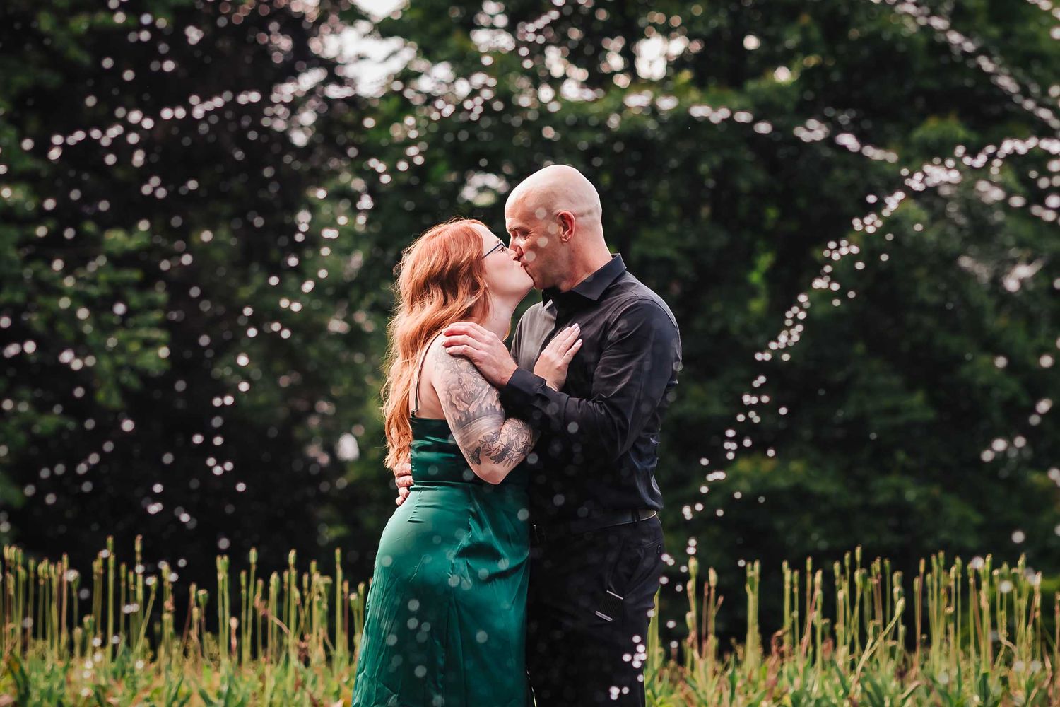 Droplets of water from a fountain frame a passionate kiss during a Boston engagement session in the Public Garden