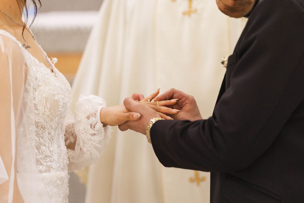 Close-up of hands during the ring exchange ceremony at a Catholic wedding.