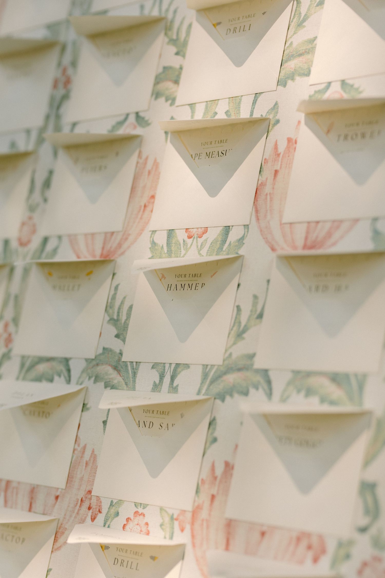 Rows of decorative place cards with watercolor cactus designs arranged in a geometric pattern at a wedding reception.