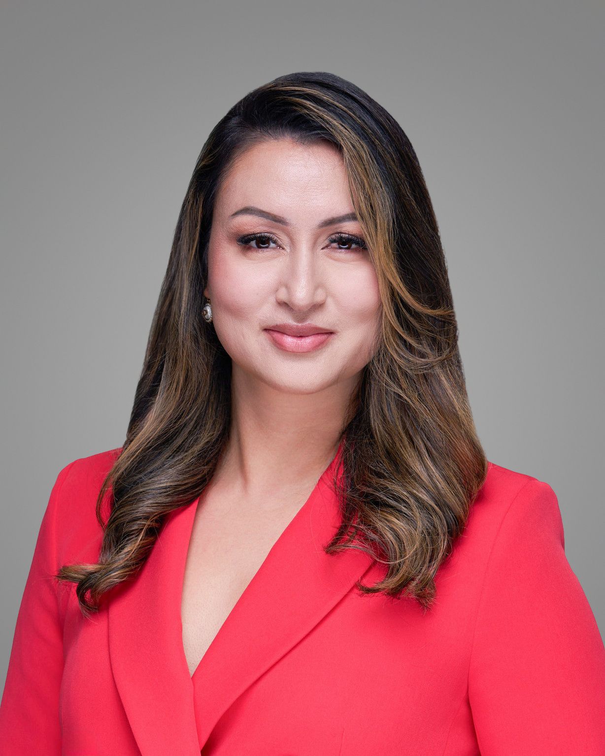 Professional portrait in red blazer against gray background.