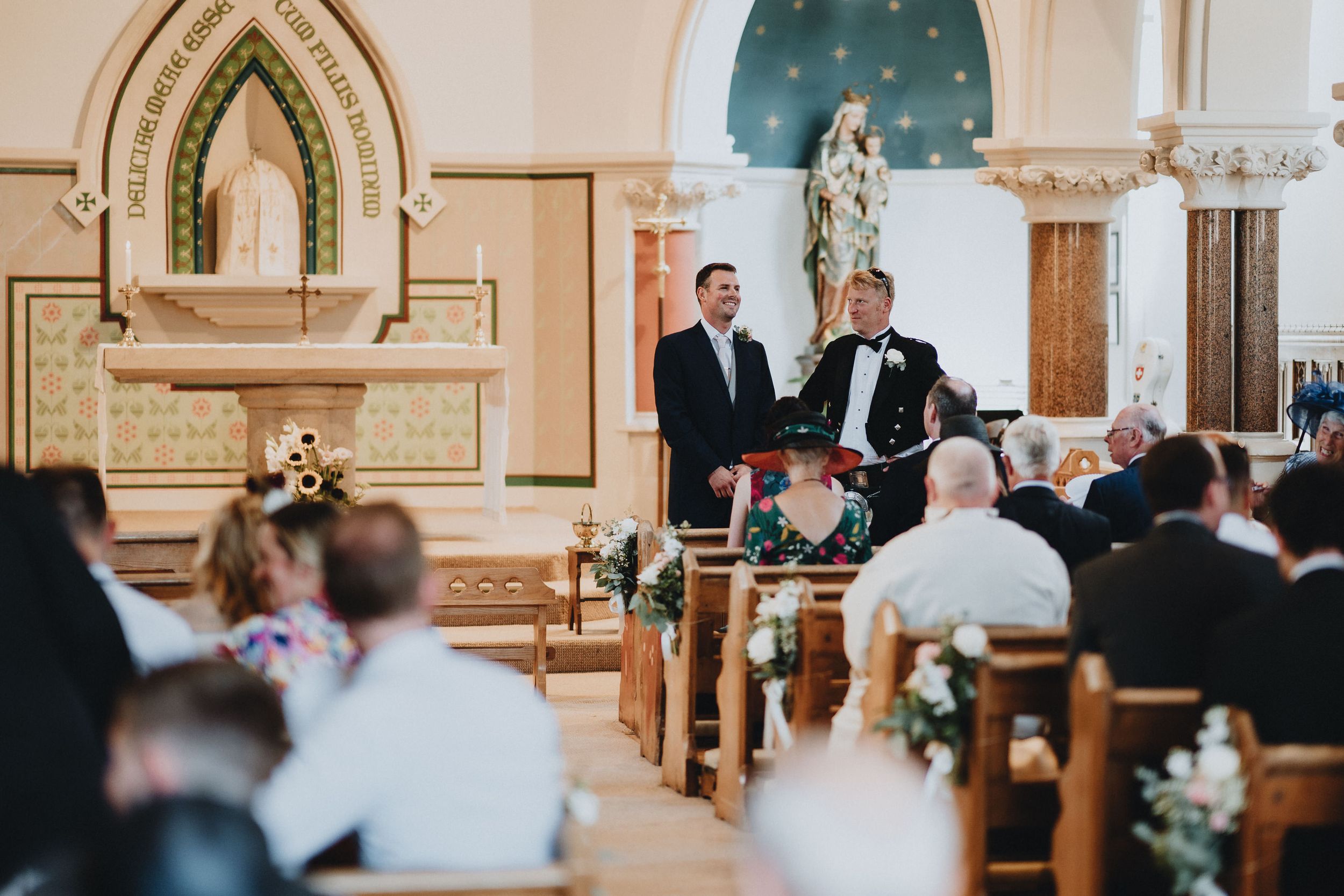 Traditional church wedding ceremony with guests seated in wooden pews and ornate religious architectural details.