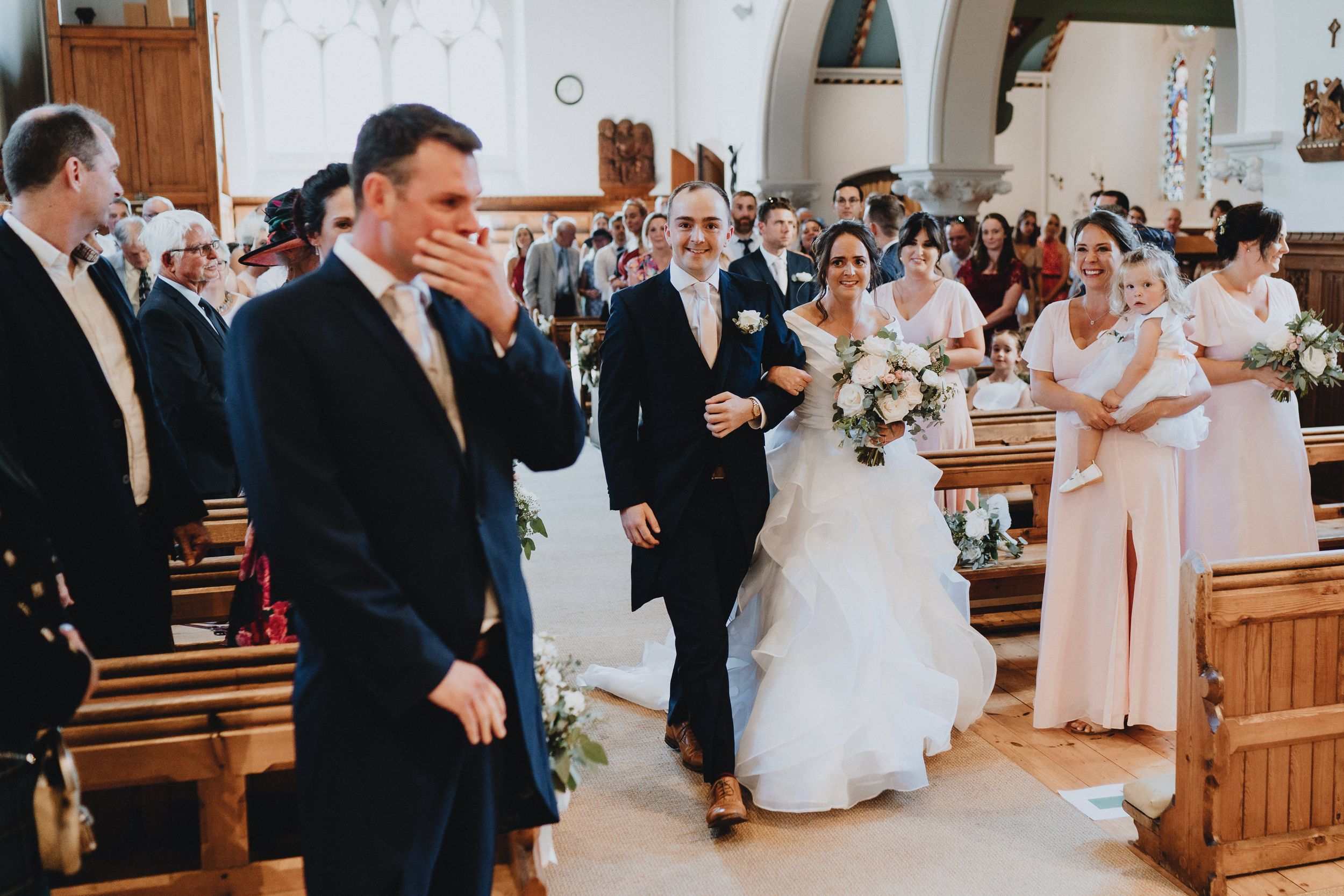 Wedding celebration inside a traditional church with guests witnessing a joyful moment during the ceremony.