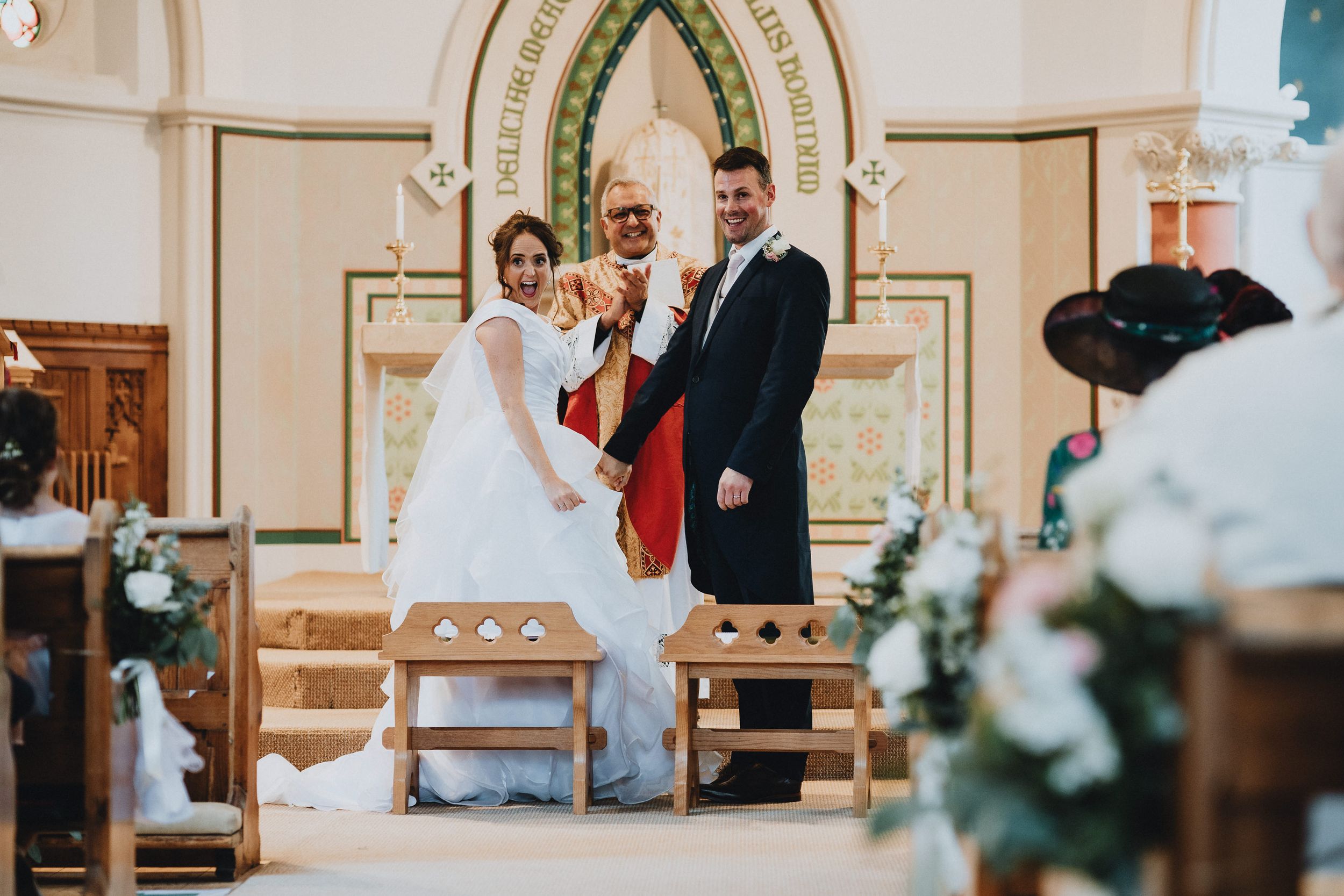 A wedding ceremony takes place in a beautiful church interior with ornate architecture and floral decorations.