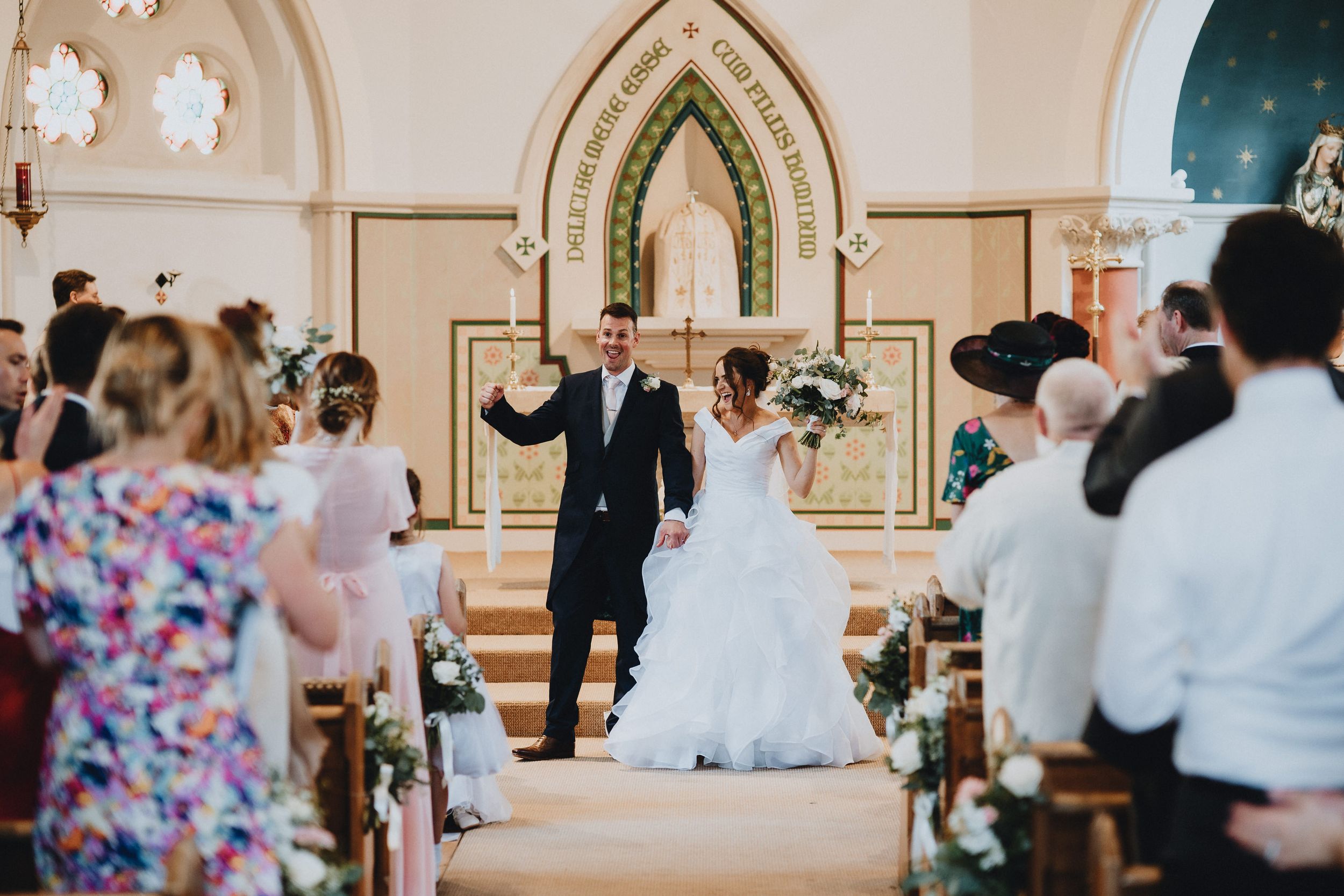 White wedding ceremony taking place in an ornate church with arched altar and floral decorations.