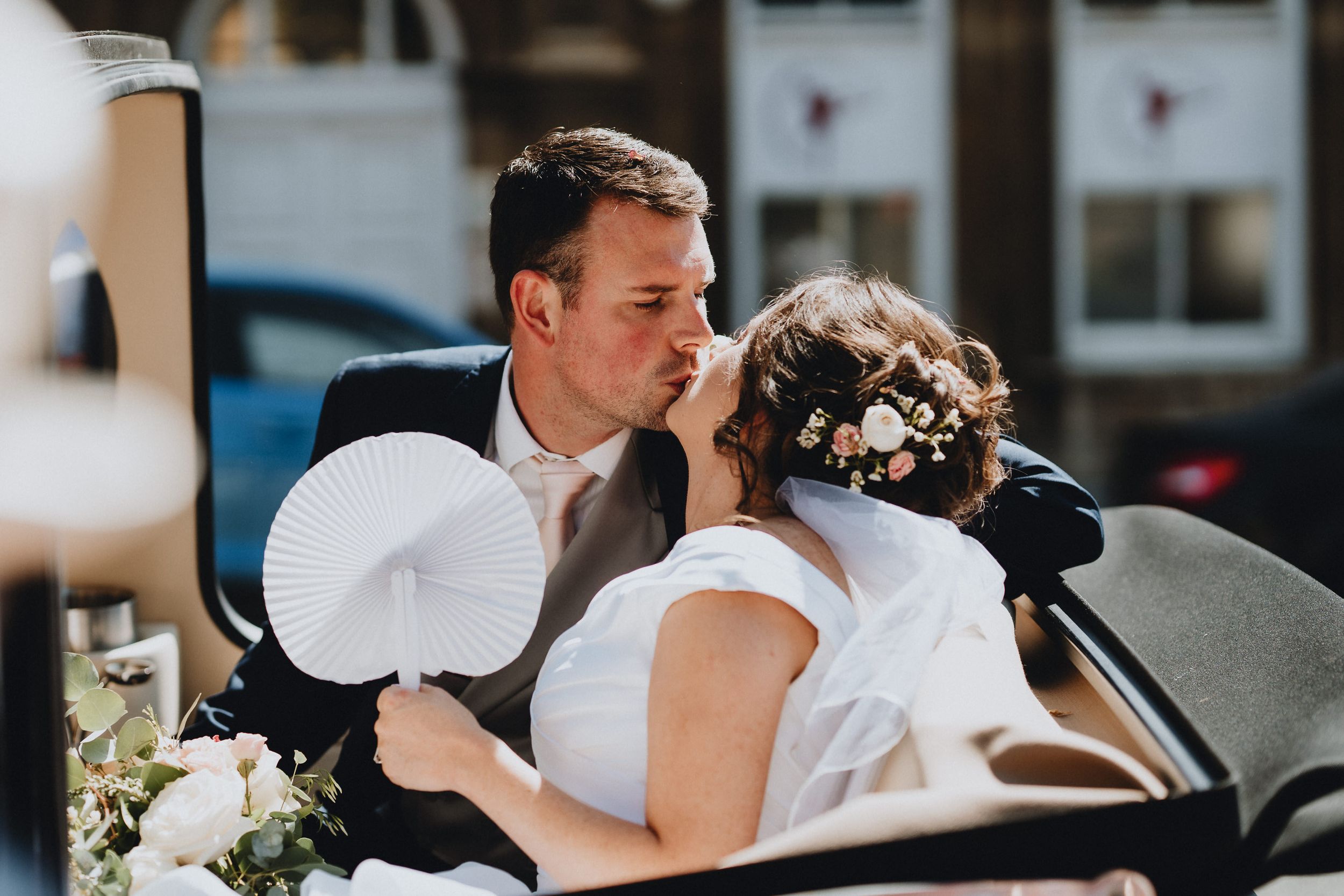 A tender romantic moment between newlyweds sharing a kiss outdoors on their wedding day.