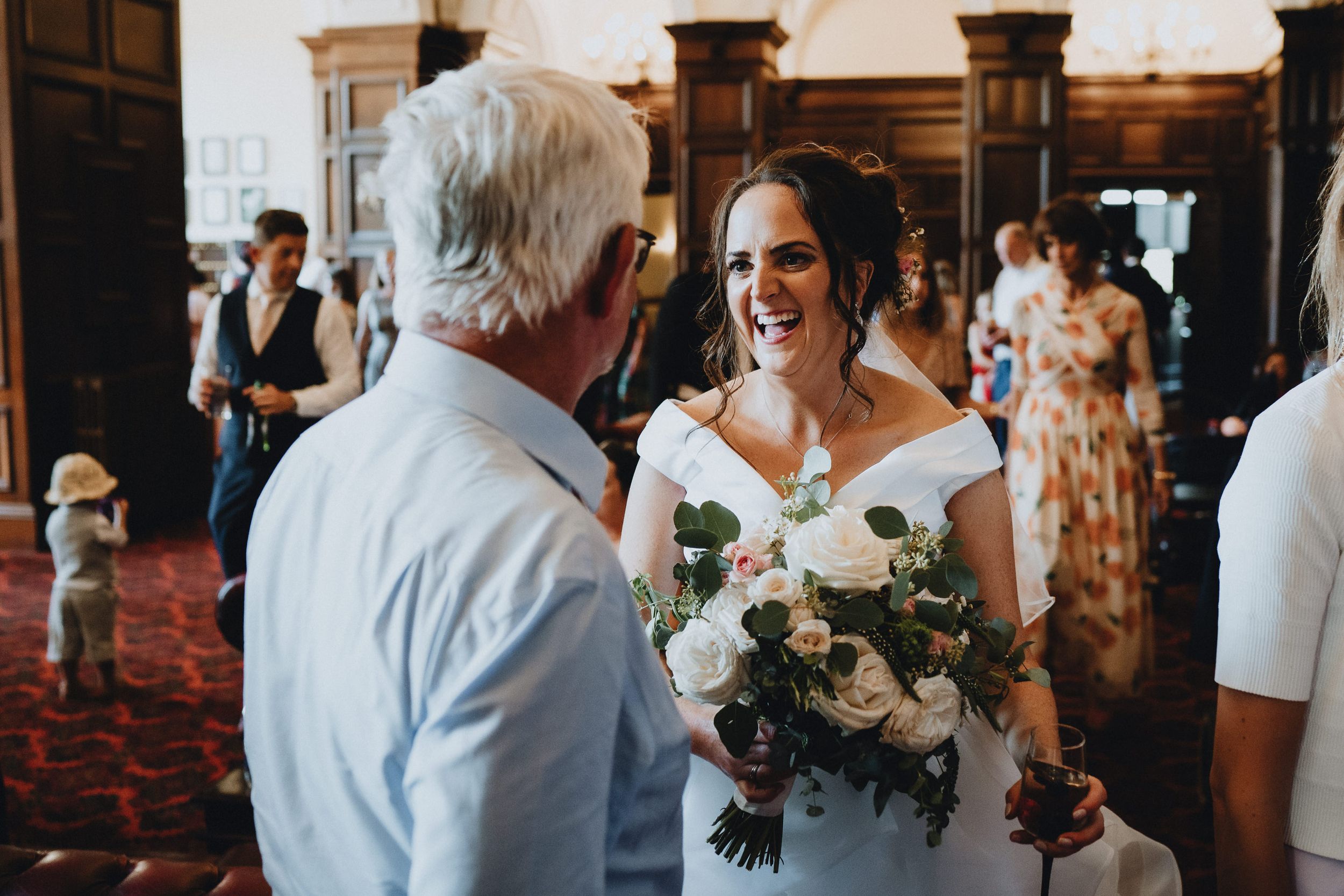 A moment of joy shared between loved ones at an indoor wedding celebration with white floral bouquet.