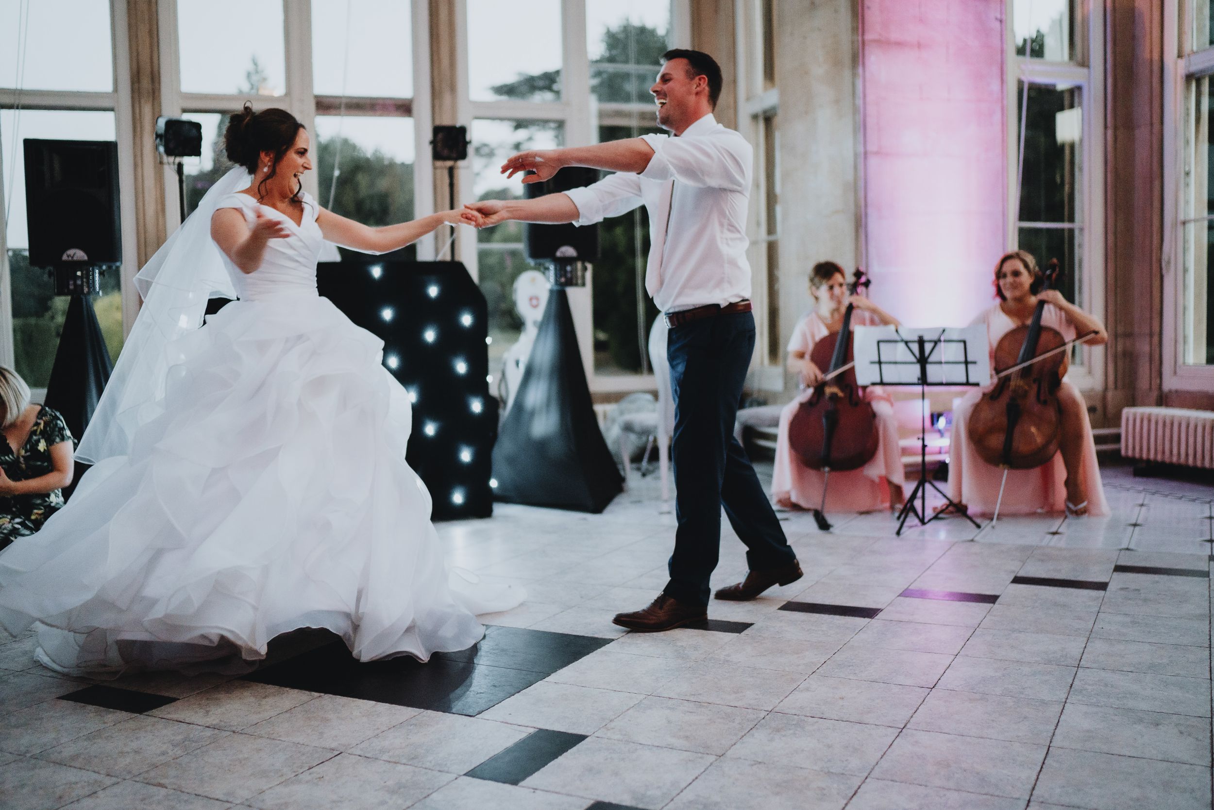 A couple dancing in formal attire at their wedding reception while musicians perform in the background.