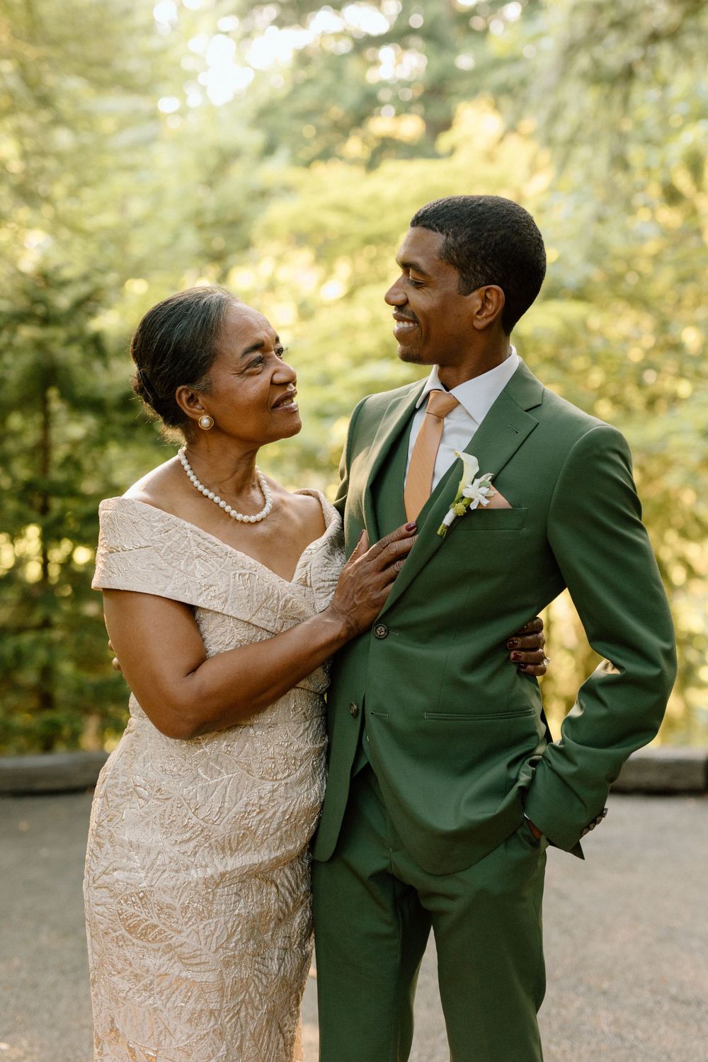 A tender moment between mother and son at a wedding, with the groom wearing a striking green suit and boutonniere.